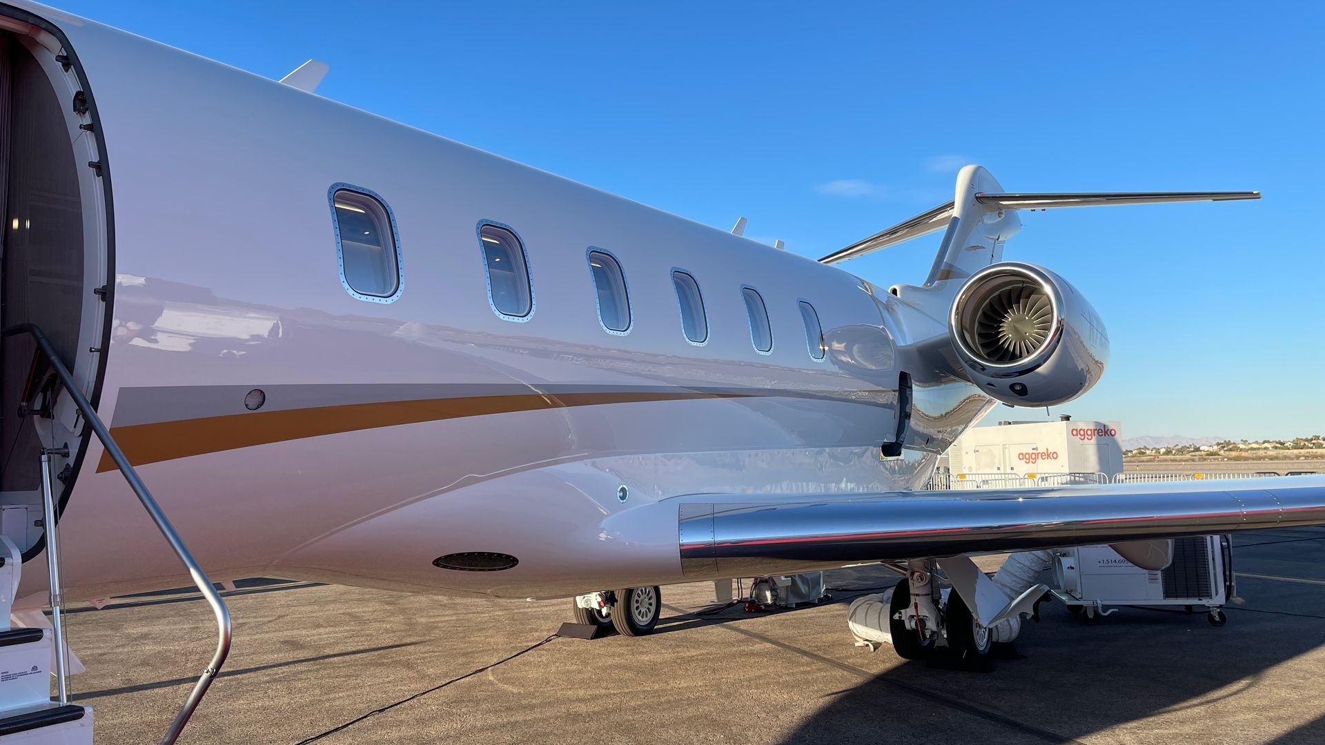 A small private jet is parked on the tarmac at an airport.
