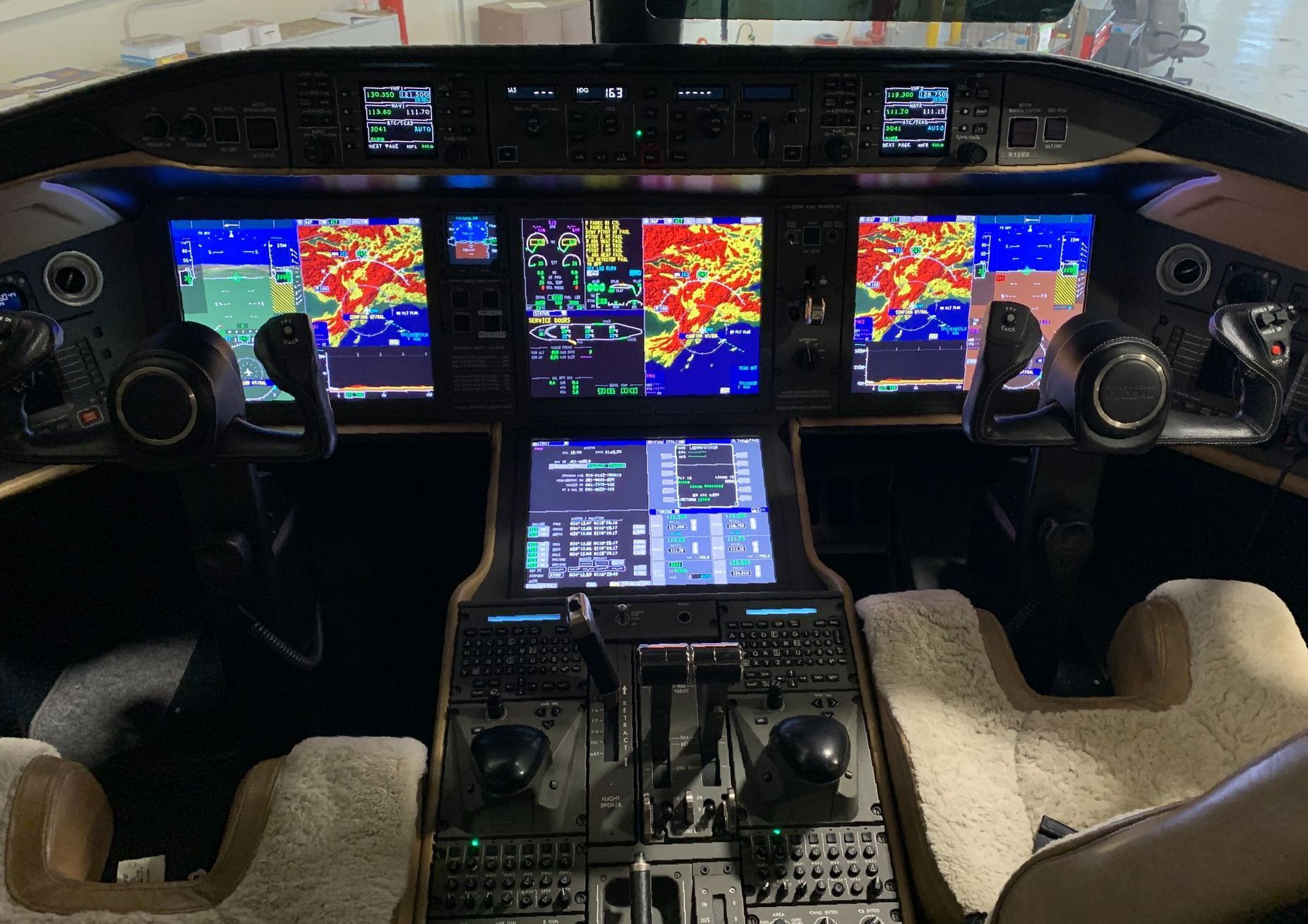 A cockpit of an airplane with many monitors and controls