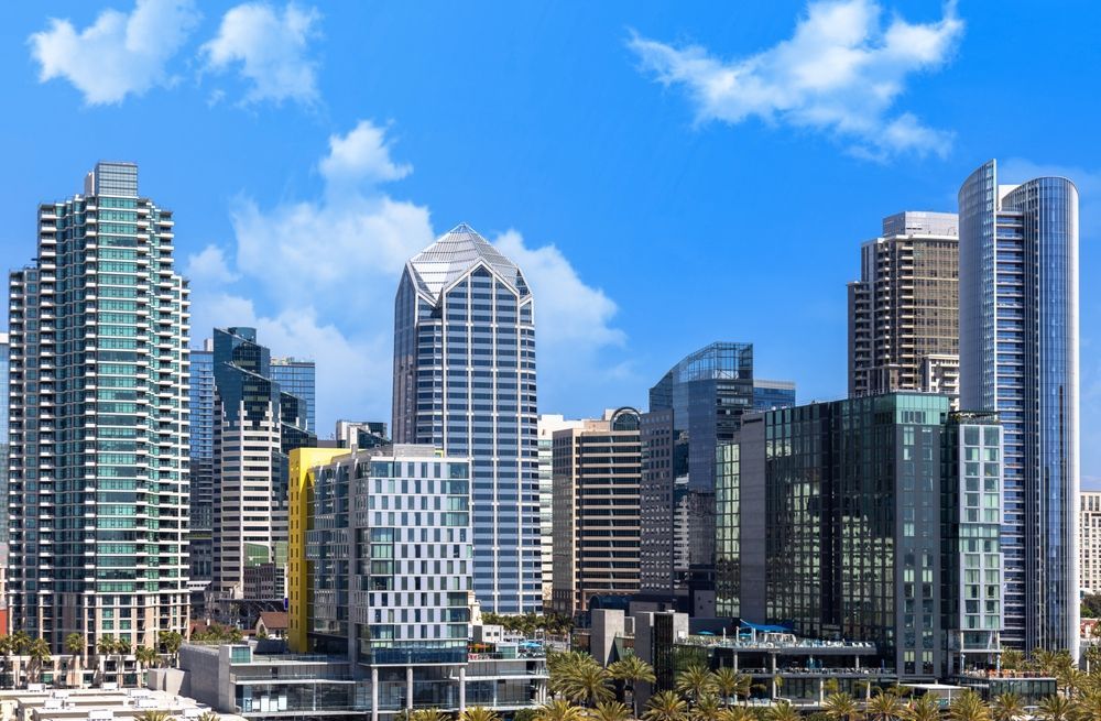A city skyline with a blue sky and clouds in the background
