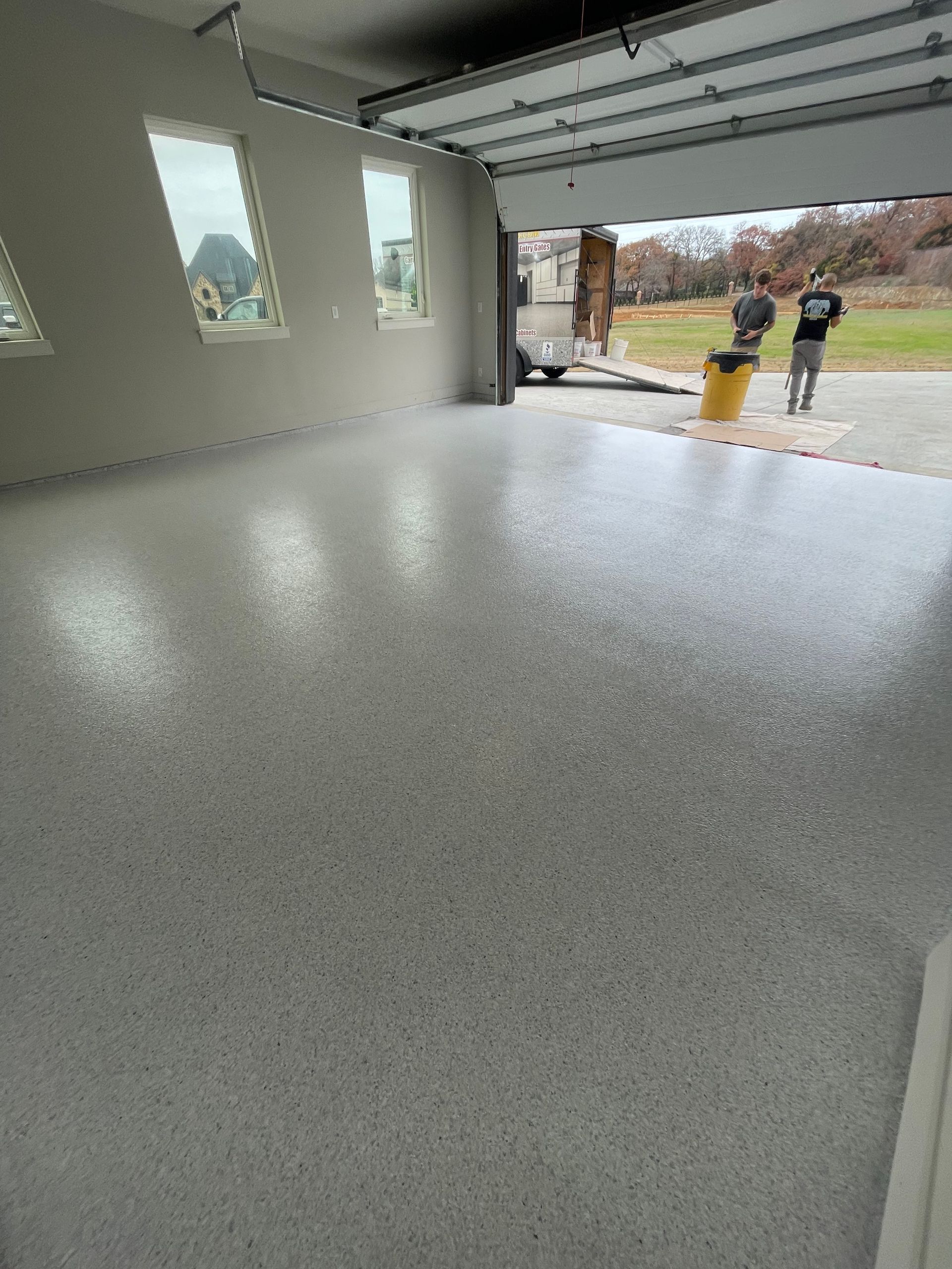 A garage with a concrete floor and a garage door open.