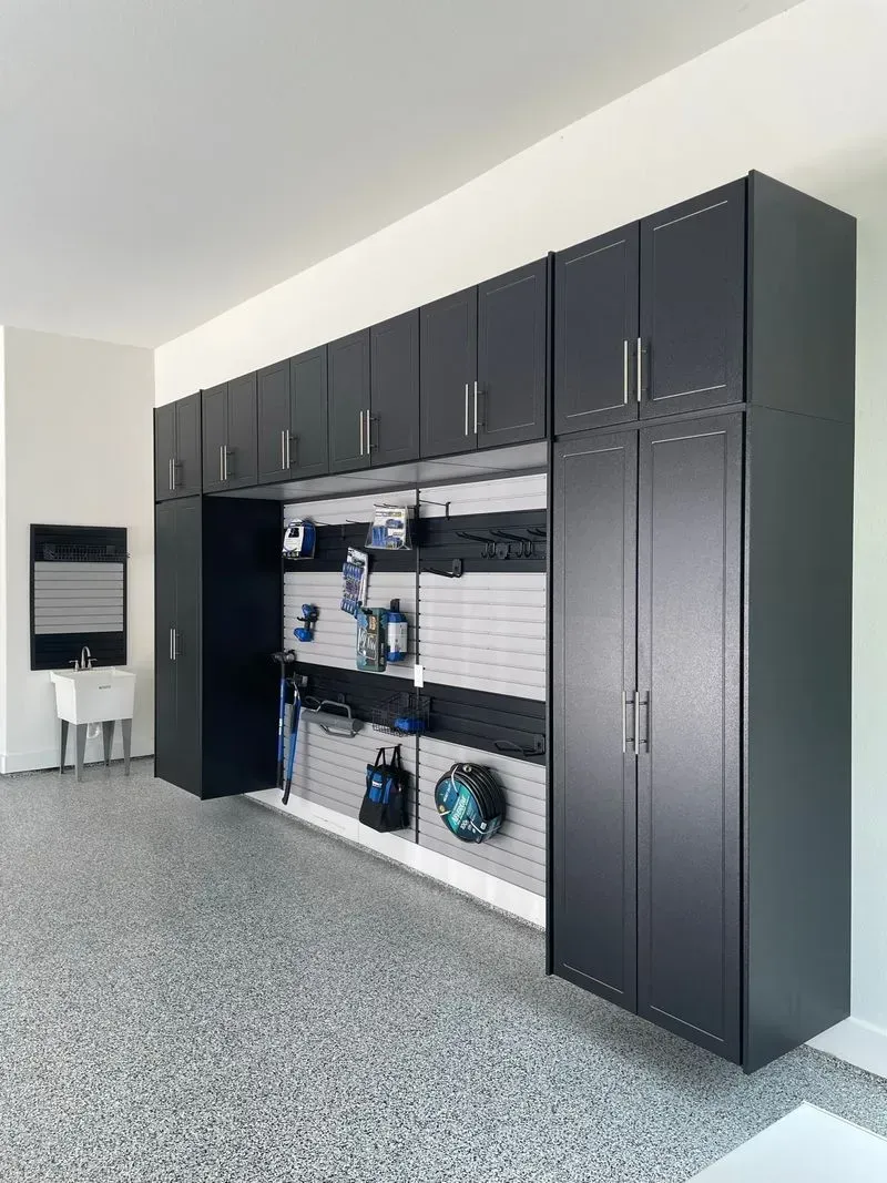 A garage with lots of black cabinets and a sink.