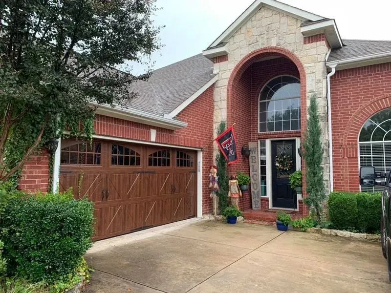 A red brick house with a brown garage door and a black door.