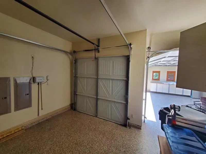 A garage with a garage door open and a table with a laptop on it.
