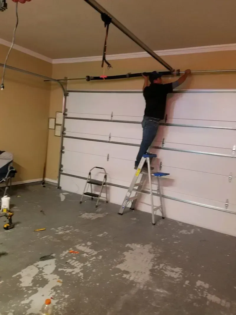 A man on a ladder working on a garage door