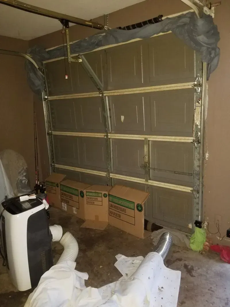 A garage with a broken garage door and boxes on the floor.