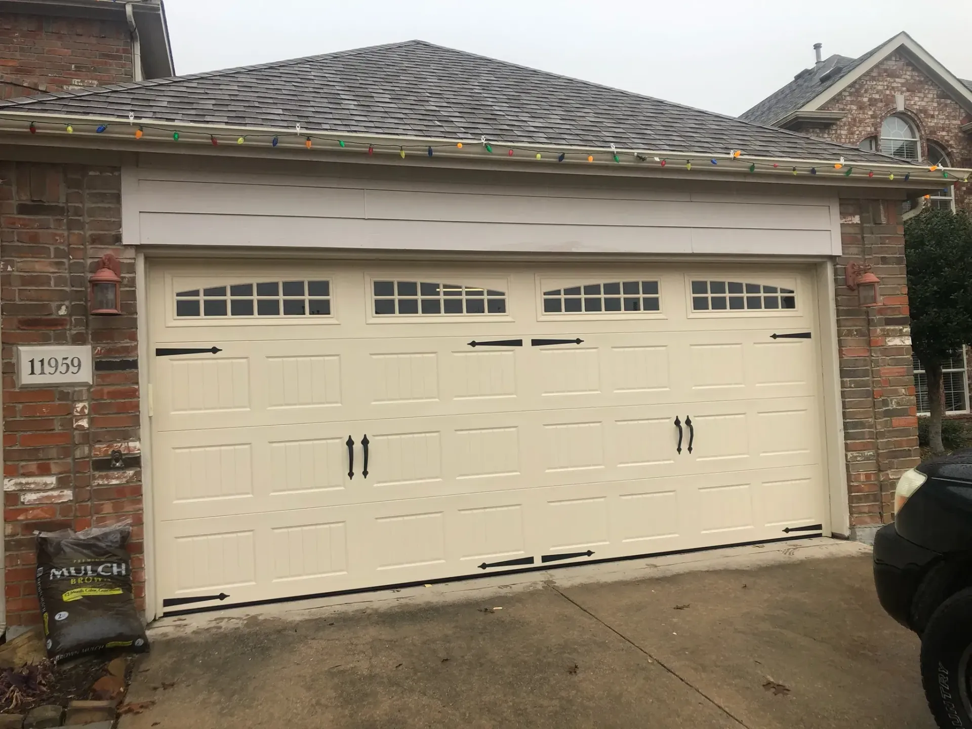A white garage door is sitting in front of a brick house.
