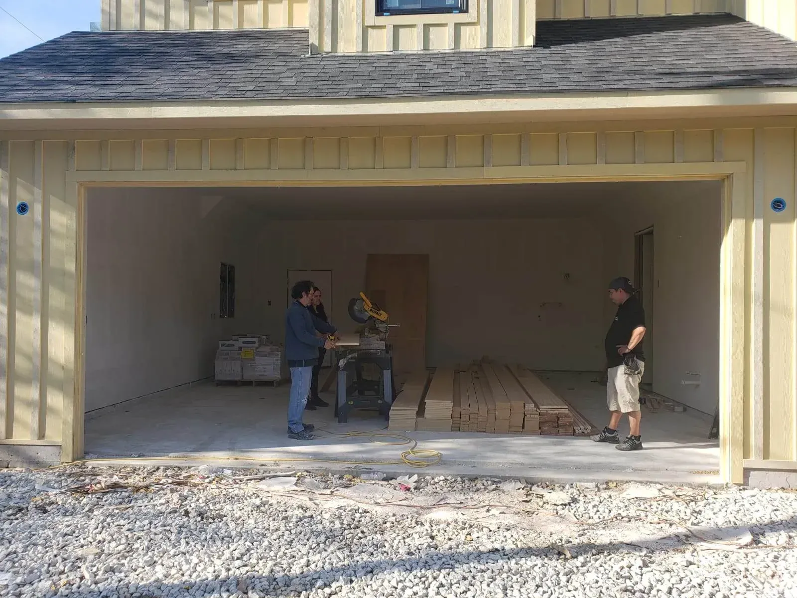 Two men are standing in front of a garage door that is open.