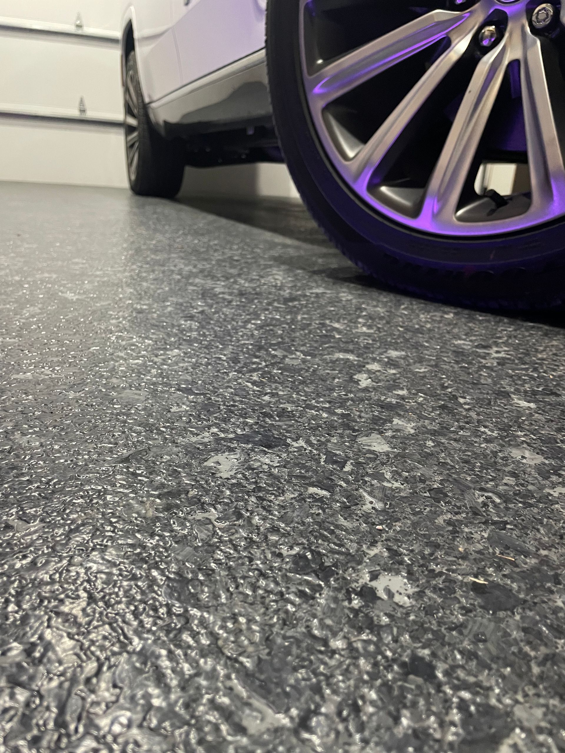 A car is parked in a garage with a purple wheel.