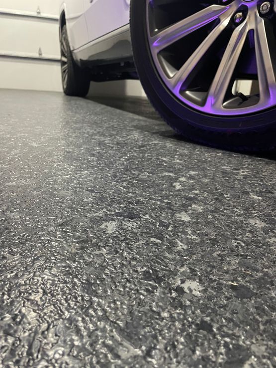 A car is parked in a garage with a purple wheel.