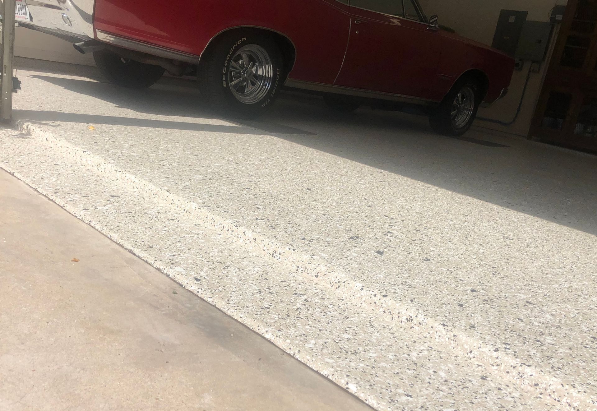 A red car is parked in a garage on a concrete floor.