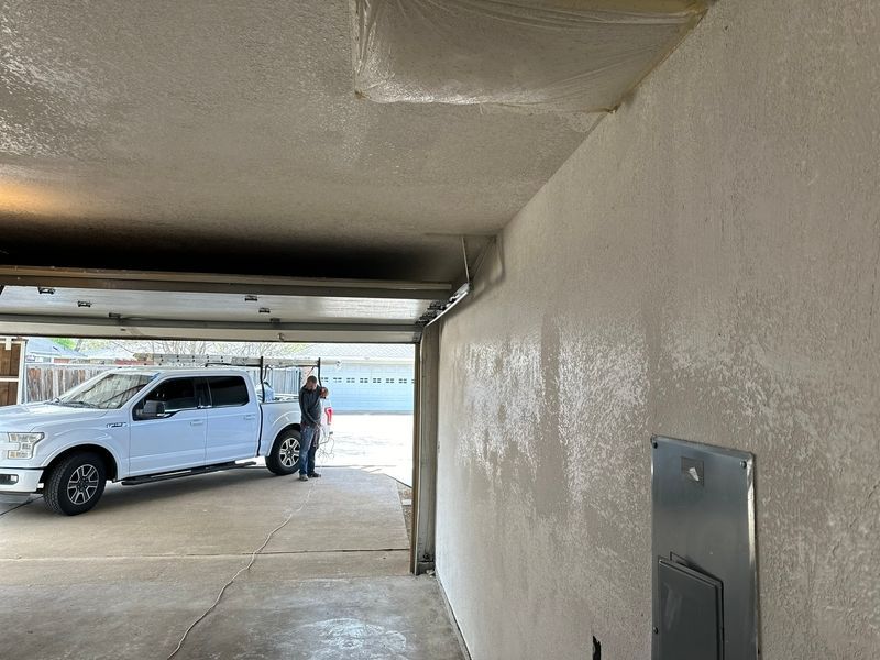 A white truck is parked in a garage next to a wall.