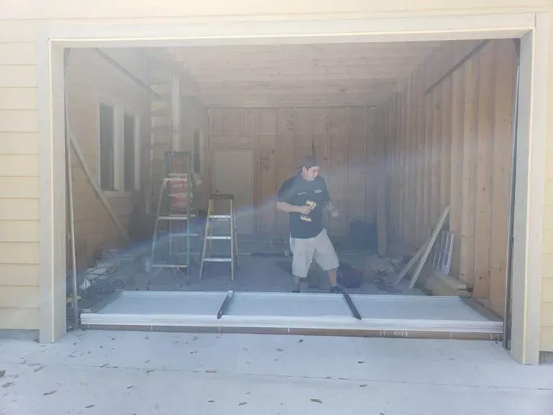 A man is standing in a garage with a ladder.