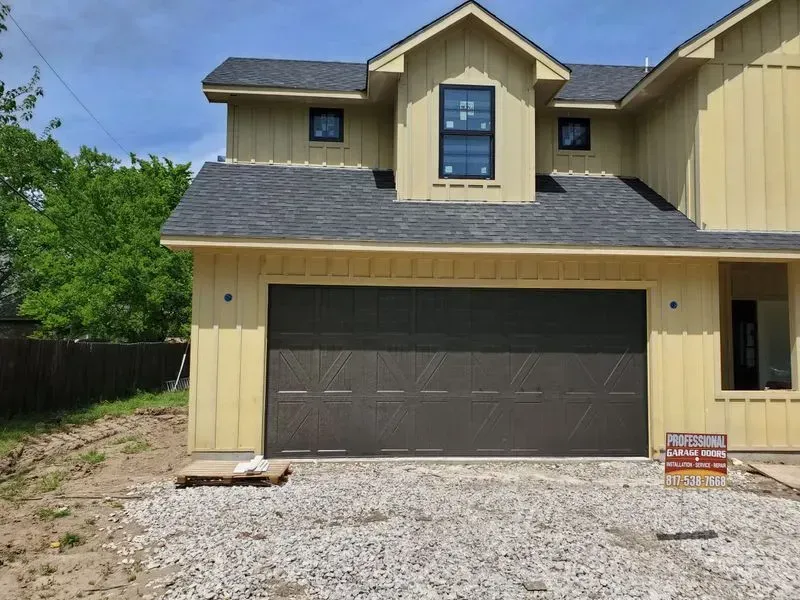 A yellow house with a black garage door and a sign that says welcome