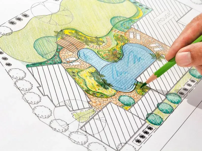 A person is drawing a garden with a green pencil.