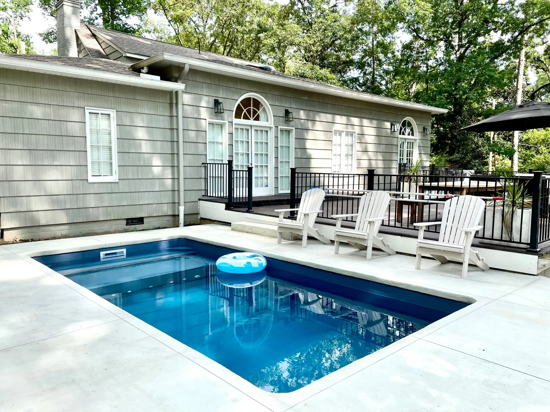 There is a large swimming pool in front of a house.