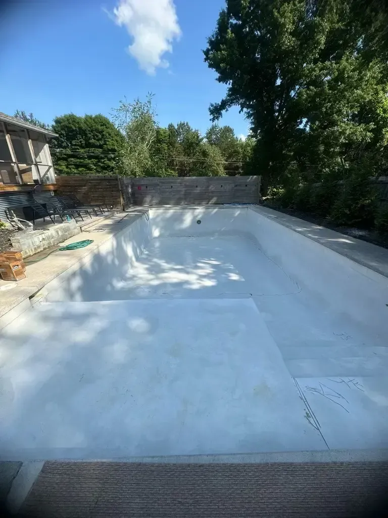 A large swimming pool is being built in the backyard of a house.