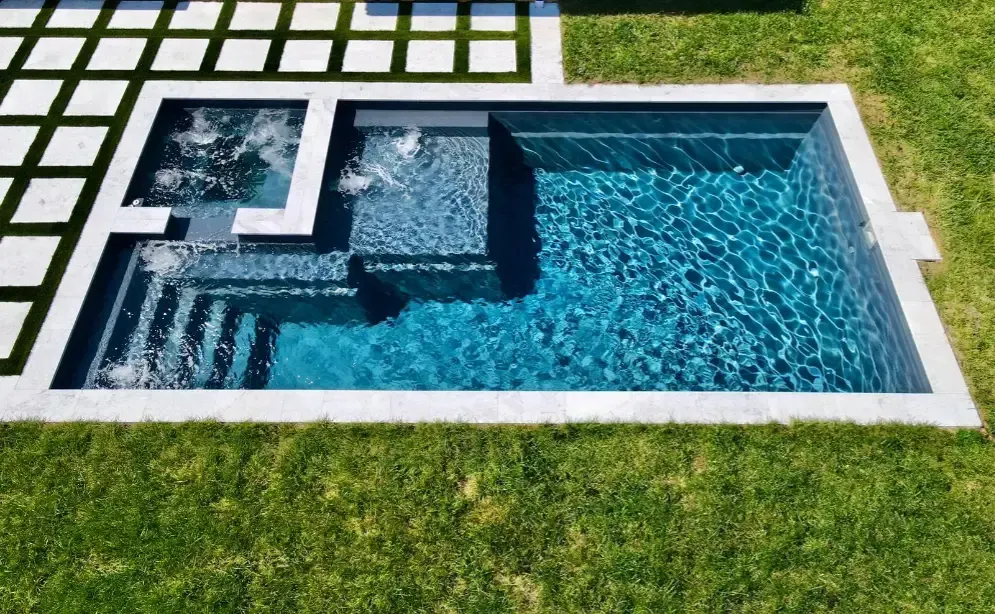 Modern plunge pool with integrated spa and geometric stone decking,compact luxury for backyard relaxation and entertainment.
