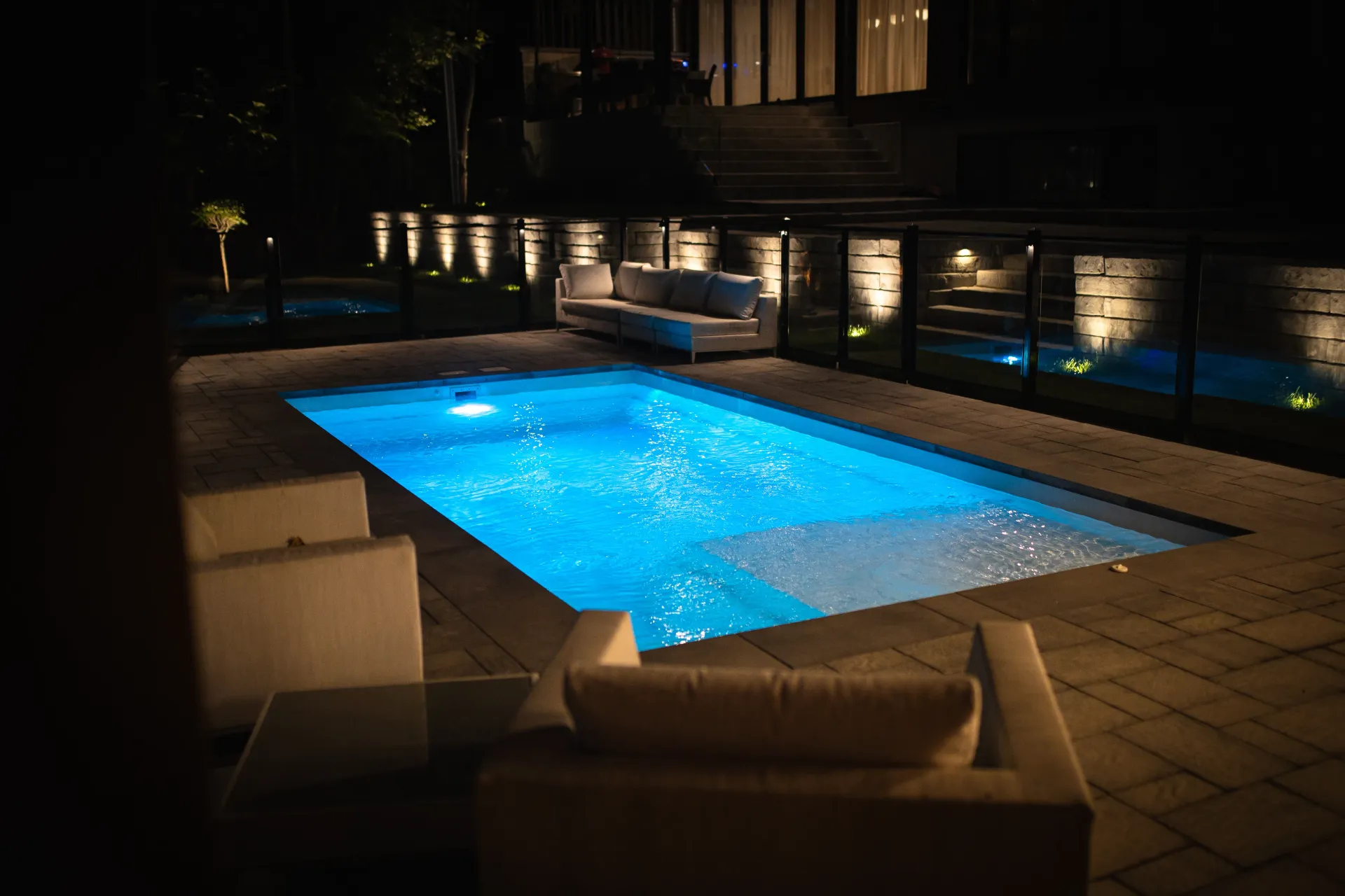 A large swimming pool is lit up at night.