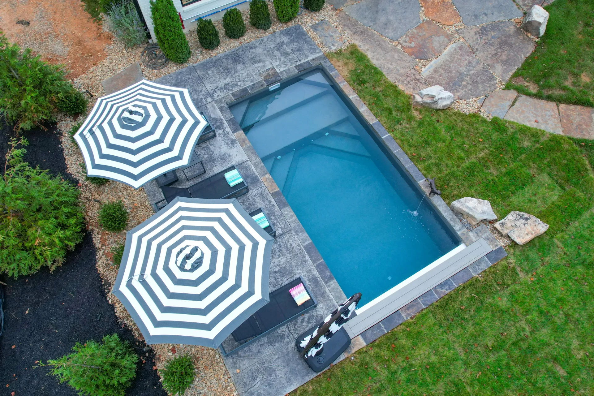 An aerial view of a swimming pool with two striped umbrellas.