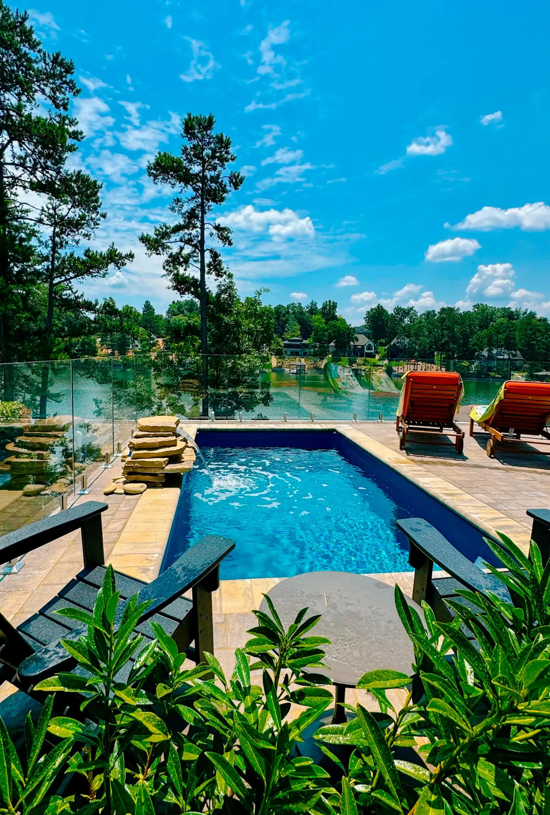 A large swimming pool surrounded by chairs and trees on a sunny day.