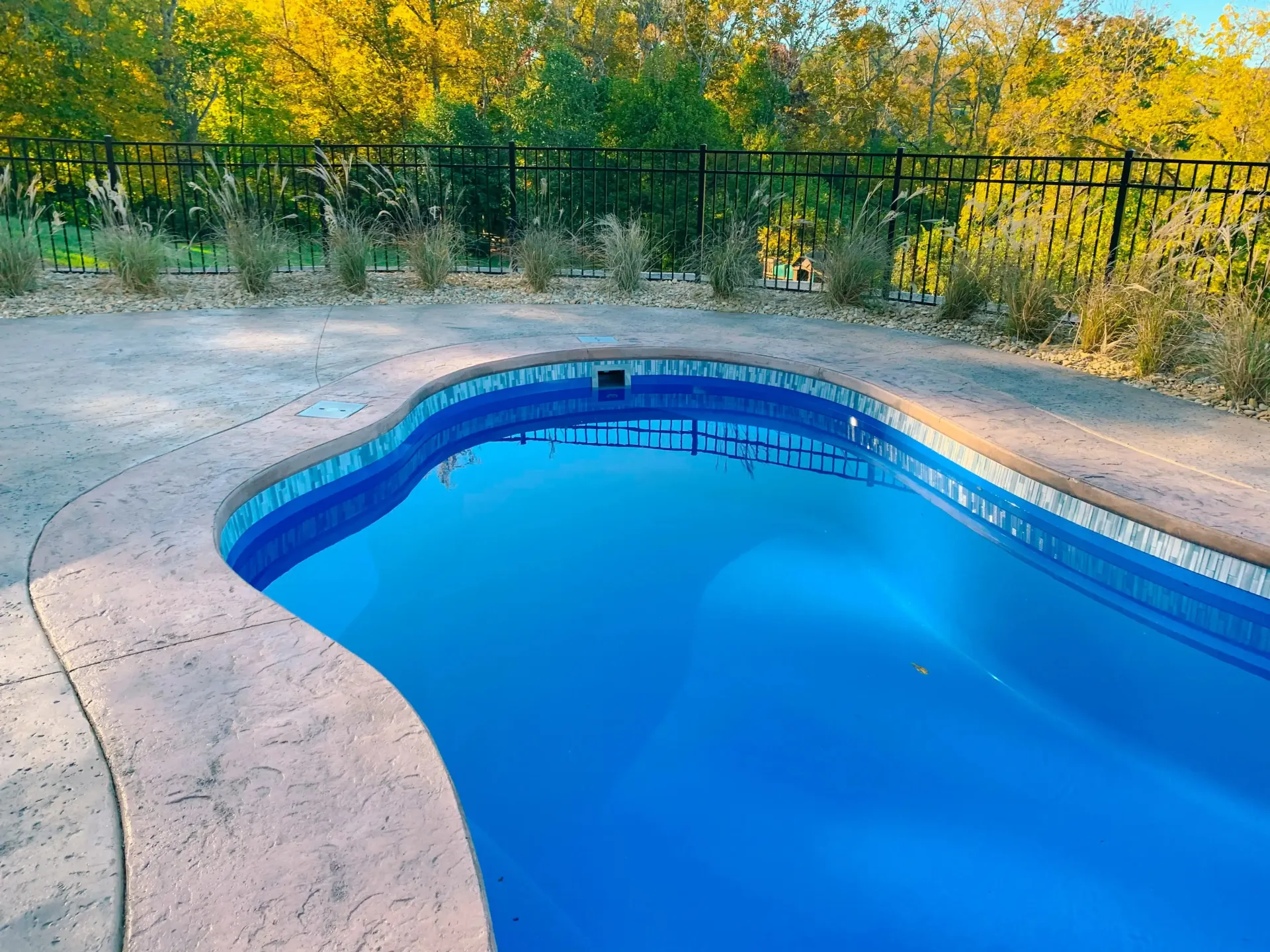 A swimming pool with blue water and a fence around it