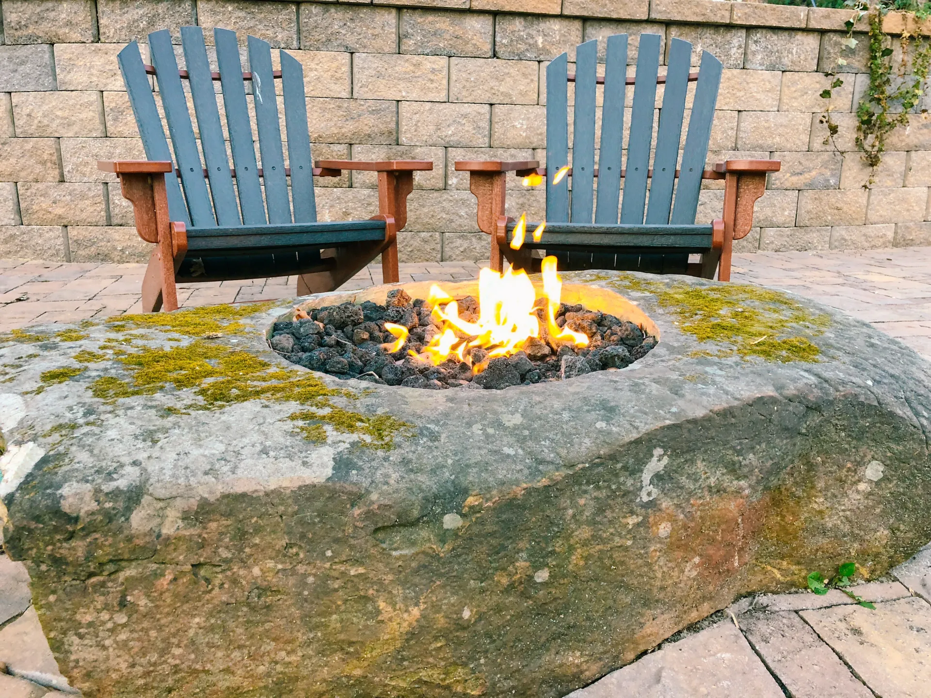 Custom tiered retaining wall and stone staircase with built-in fire pit,combining functional elevation 