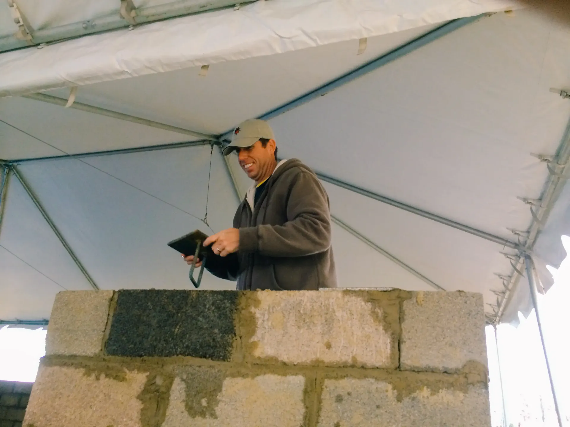 A man standing on a brick wall holding a tablet