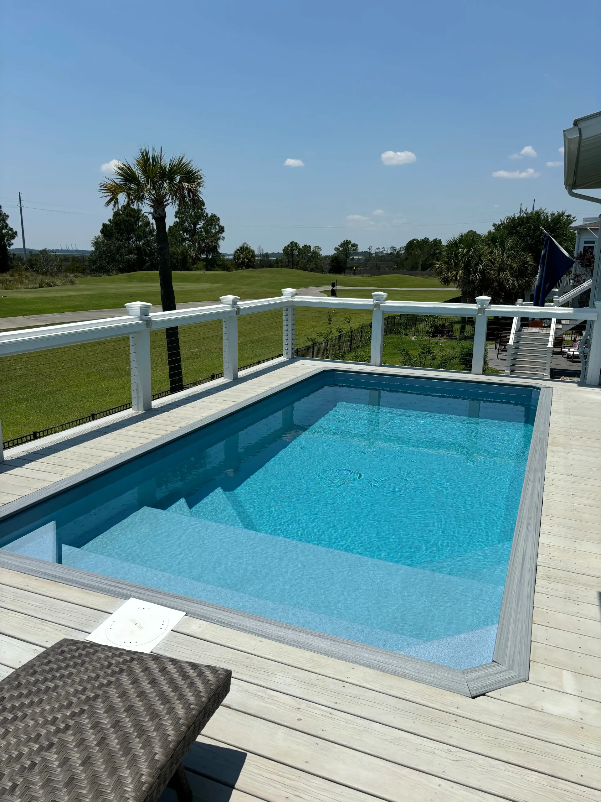A large swimming pool on a deck with a white fence