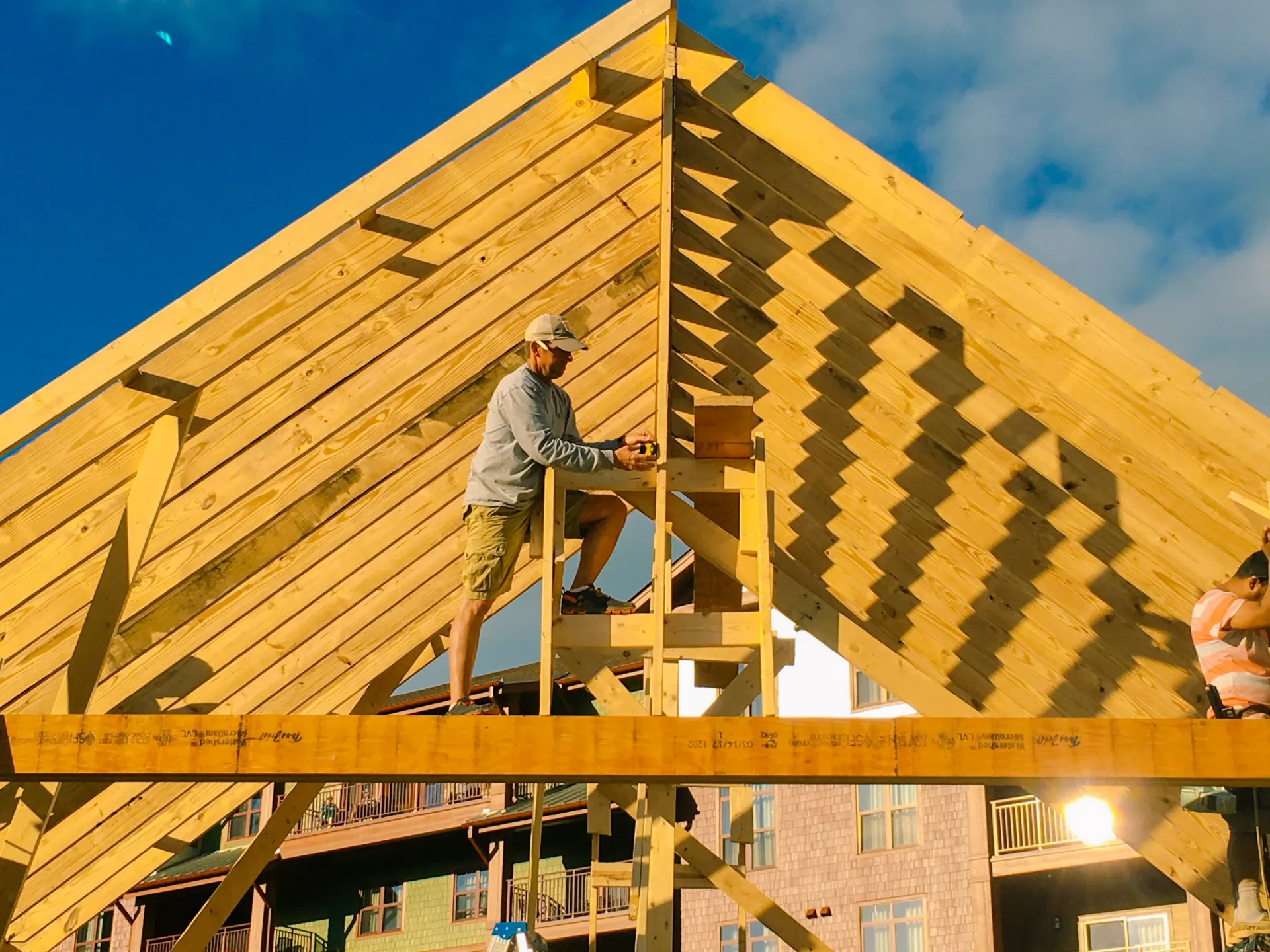 A man is working on a wooden structure on top of a building