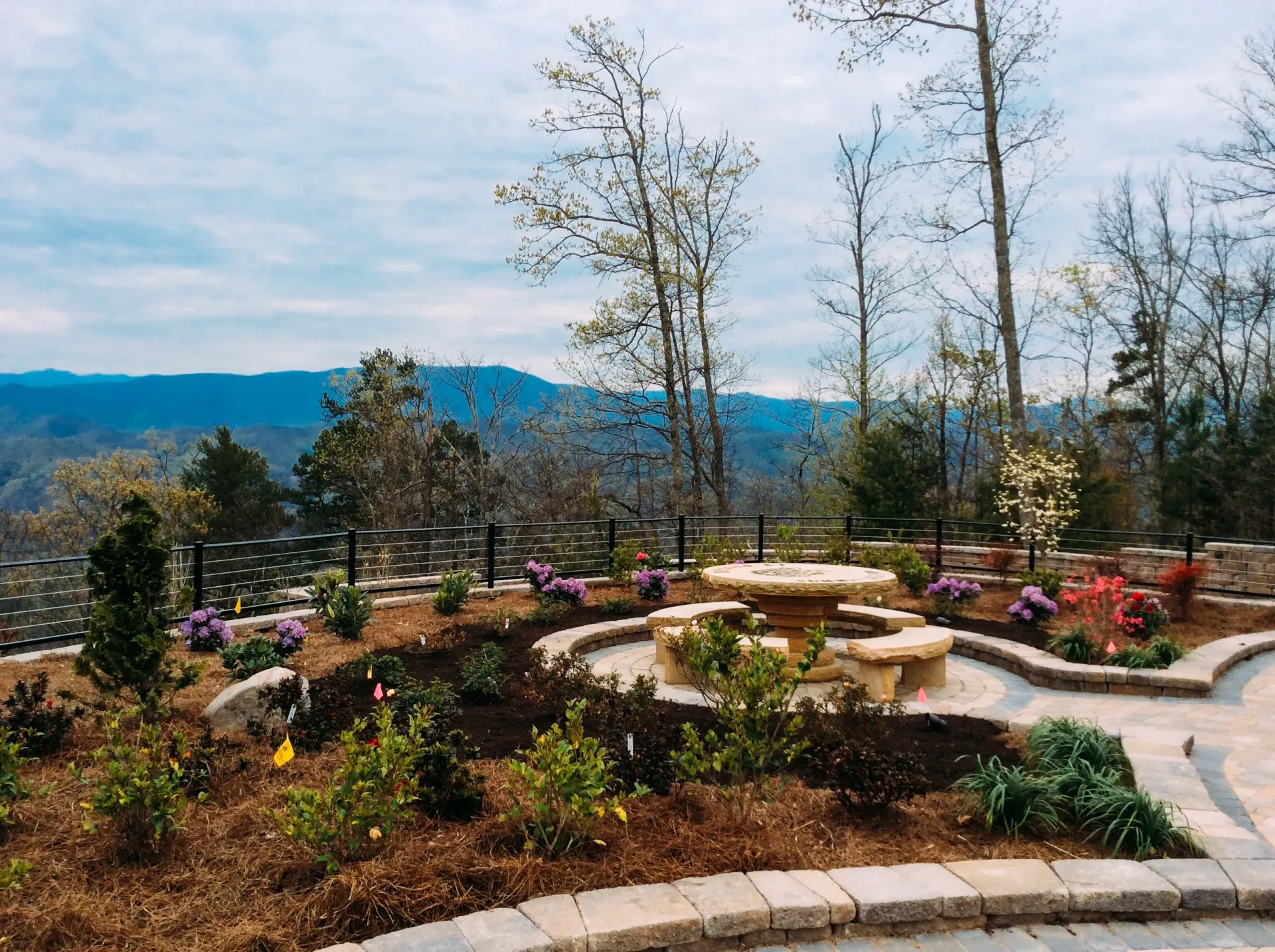 There is a fire pit in the middle of a garden with mountains in the background.