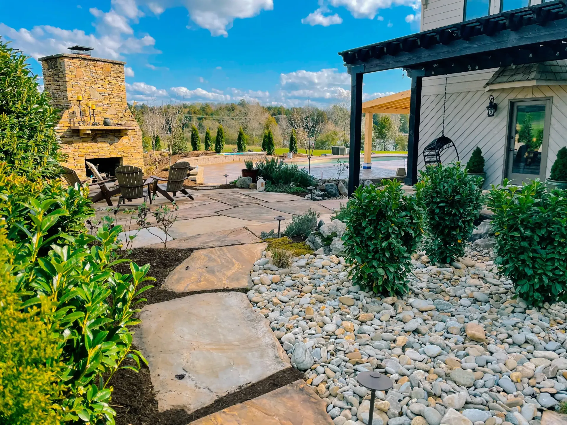 There is a stone fireplace in the backyard of a house.
