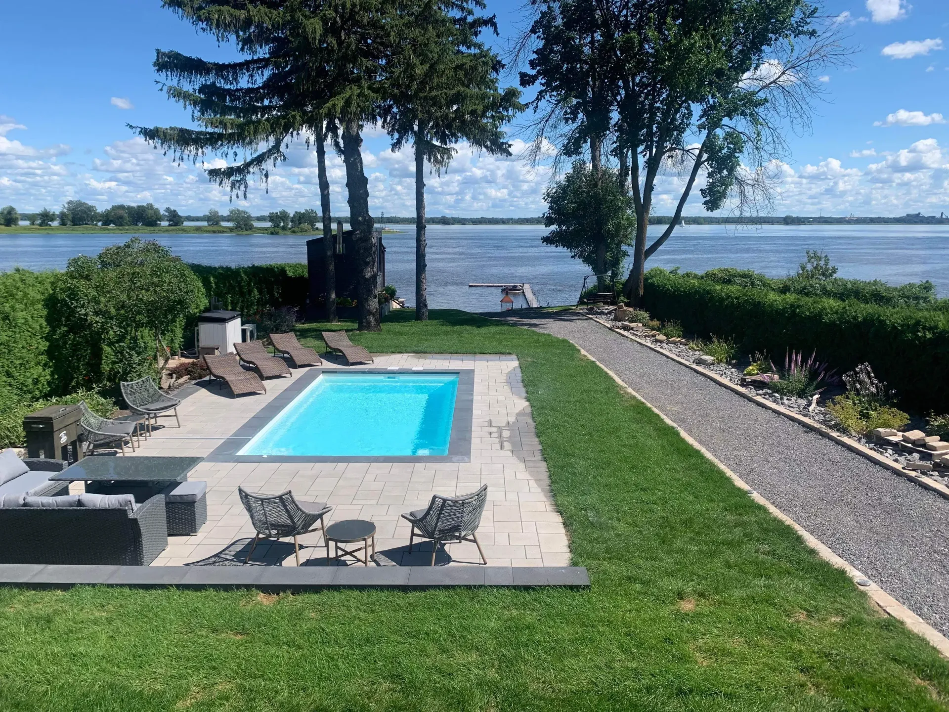 A large swimming pool in a backyard next to a lake.