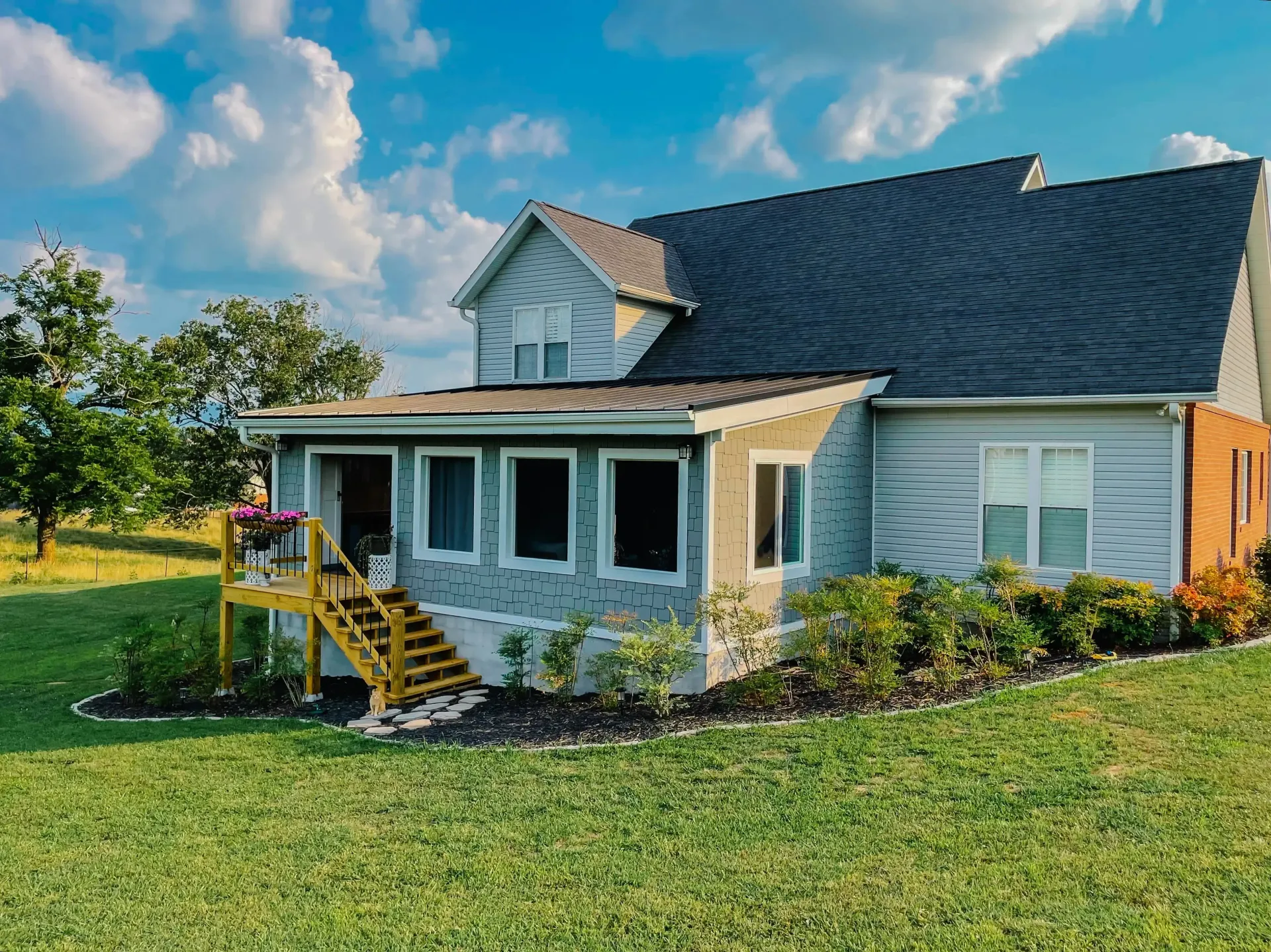 A house with a black roof is sitting on top of a lush green field.