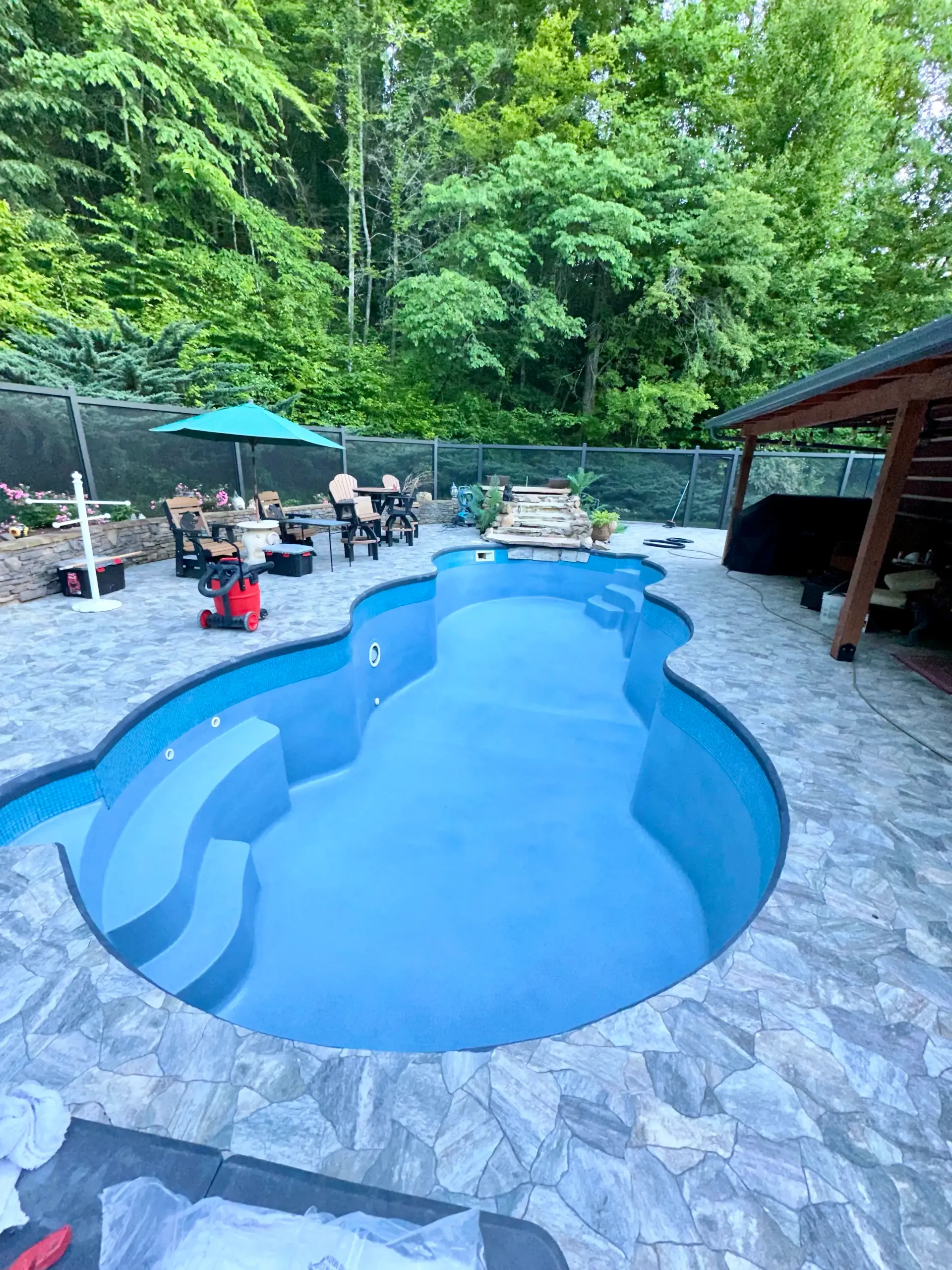 There is a large swimming pool in the middle of the backyard.