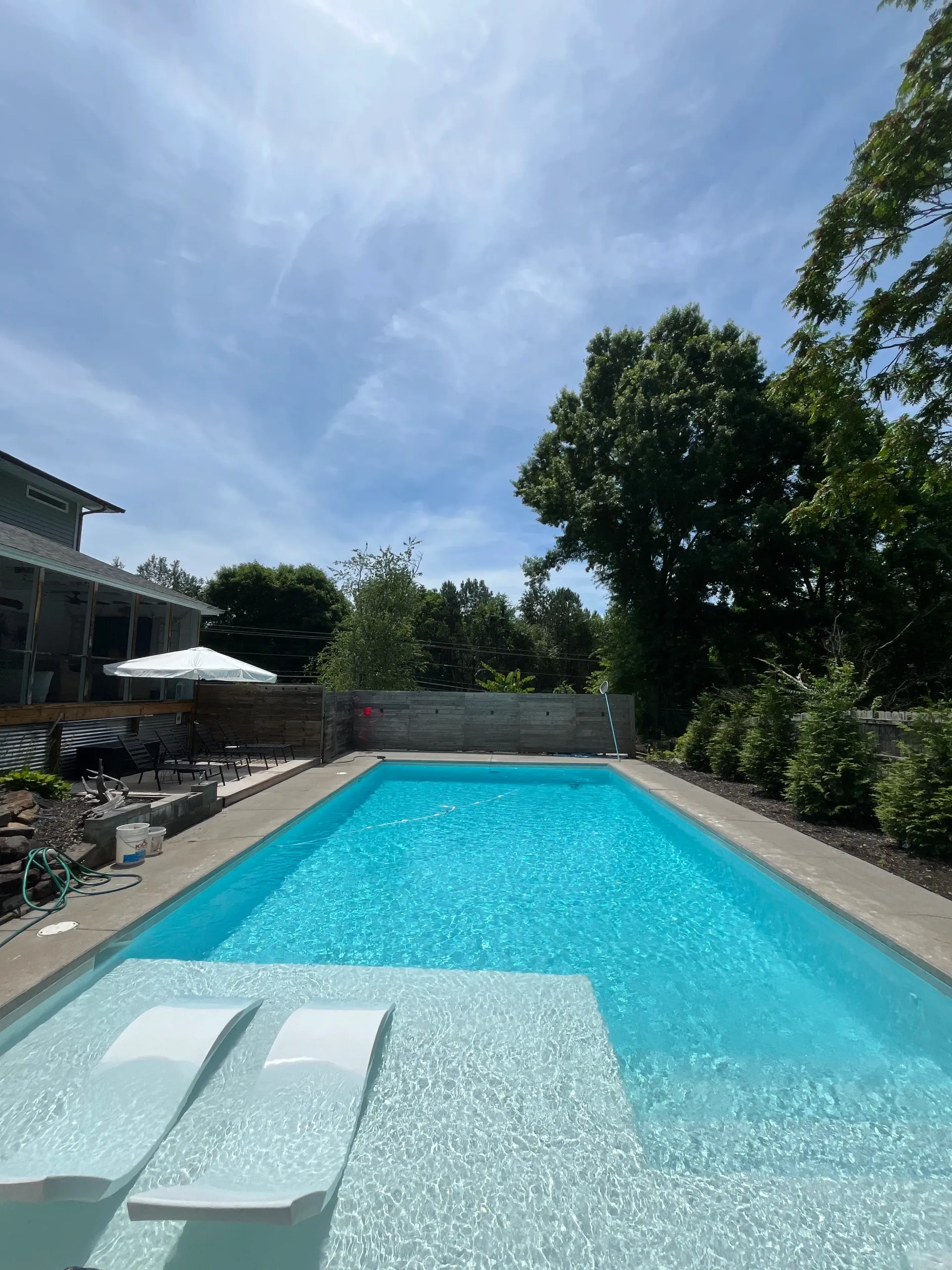 There is a large swimming pool in the backyard of a house.