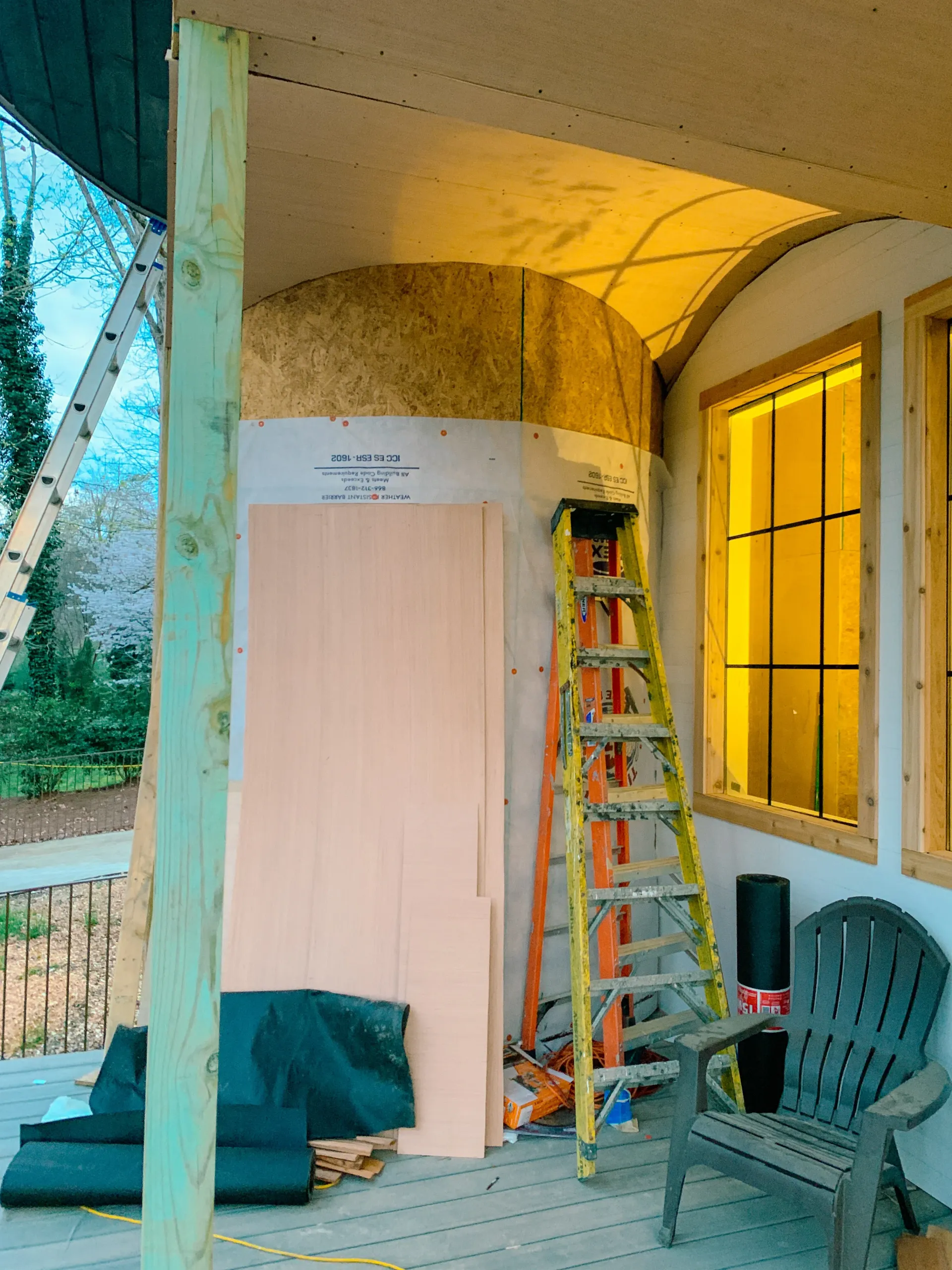 She shed under construction with wood paneling and scaffolding near arched wall
