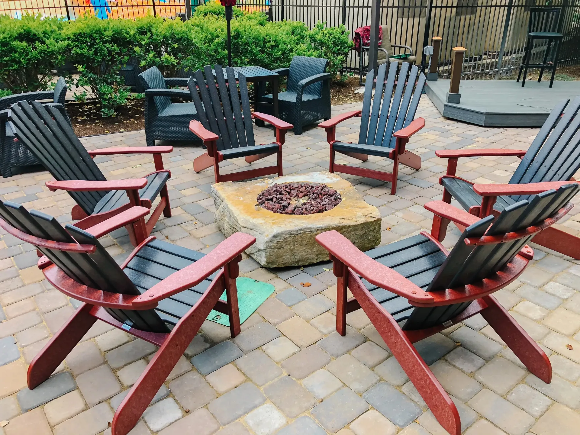 A group of chairs are sitting around a fire pit on a patio.