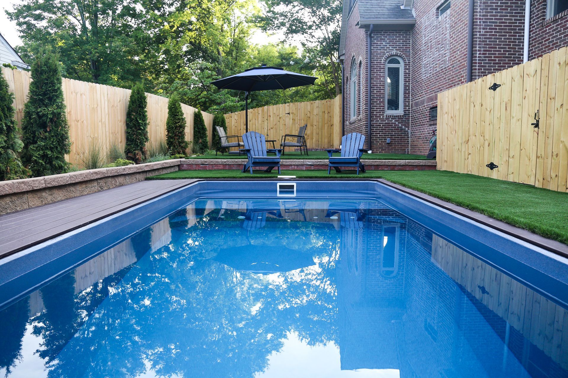 Modern rectangular plunge pool surrounded by artificial turf and wood privacy fence