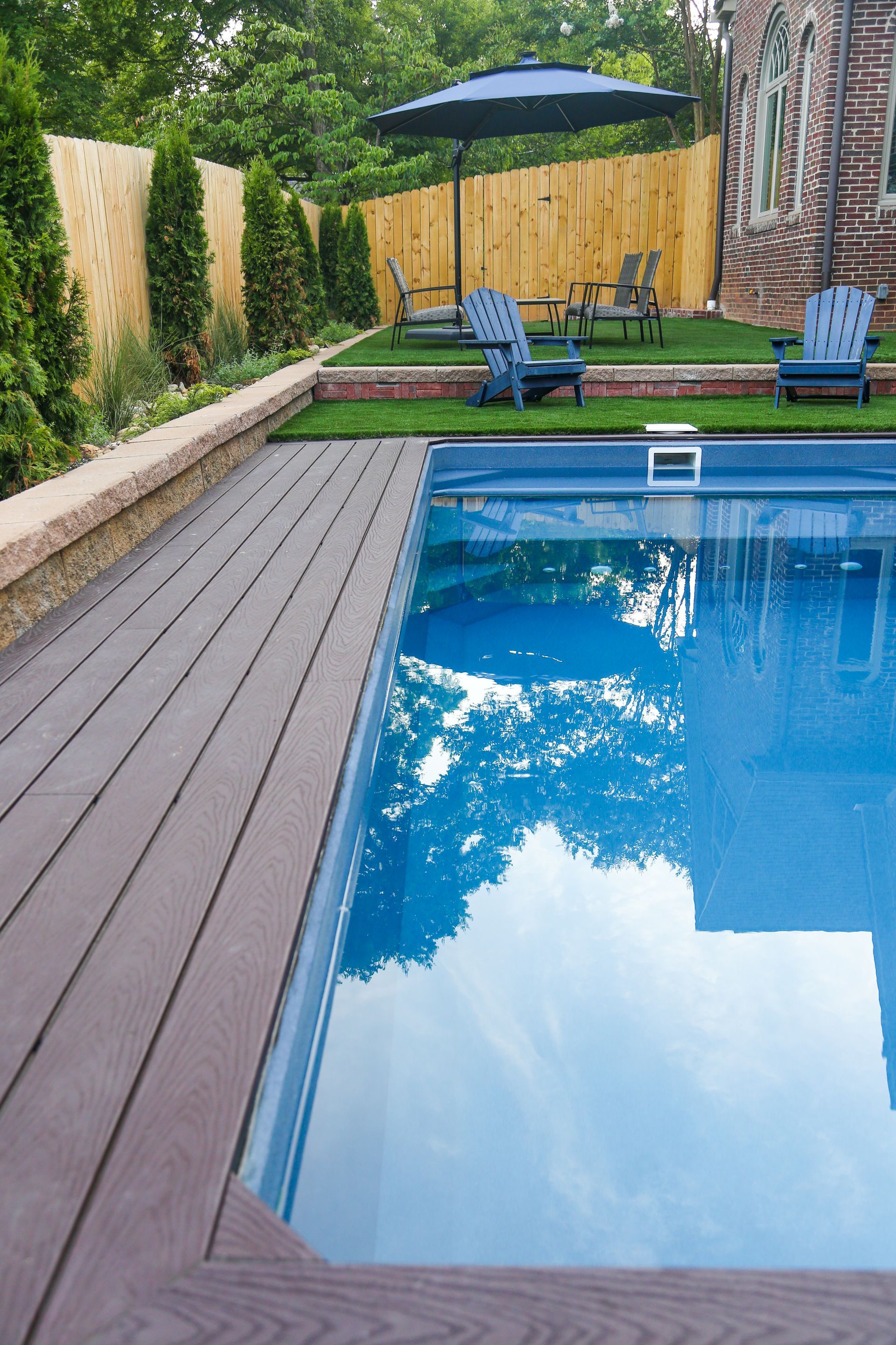 Contemporary plunge pool installation with in-pool seating in tight backyard layout