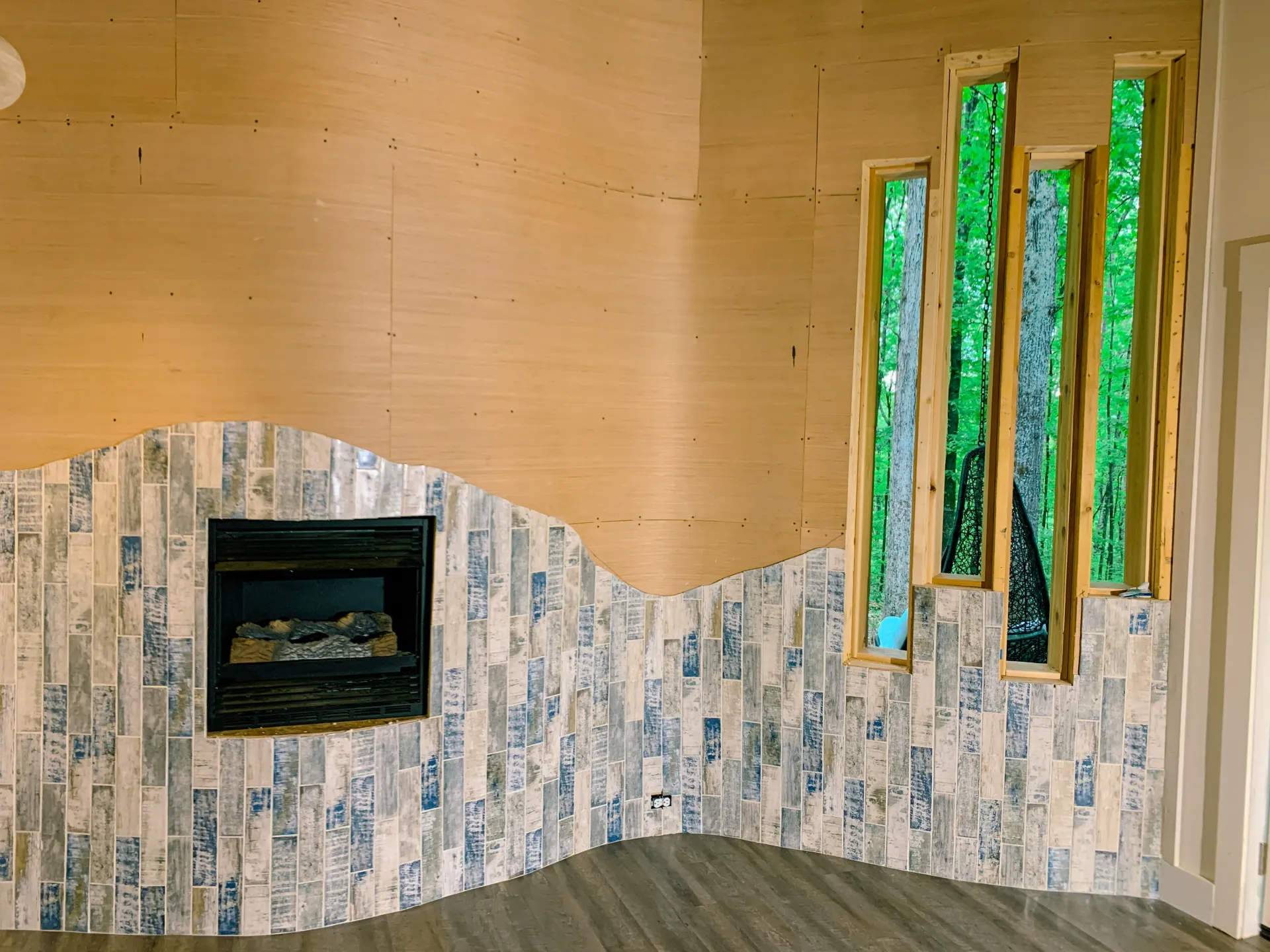 Accent fireplace wall mid-construction with blue-gray tile and window frames