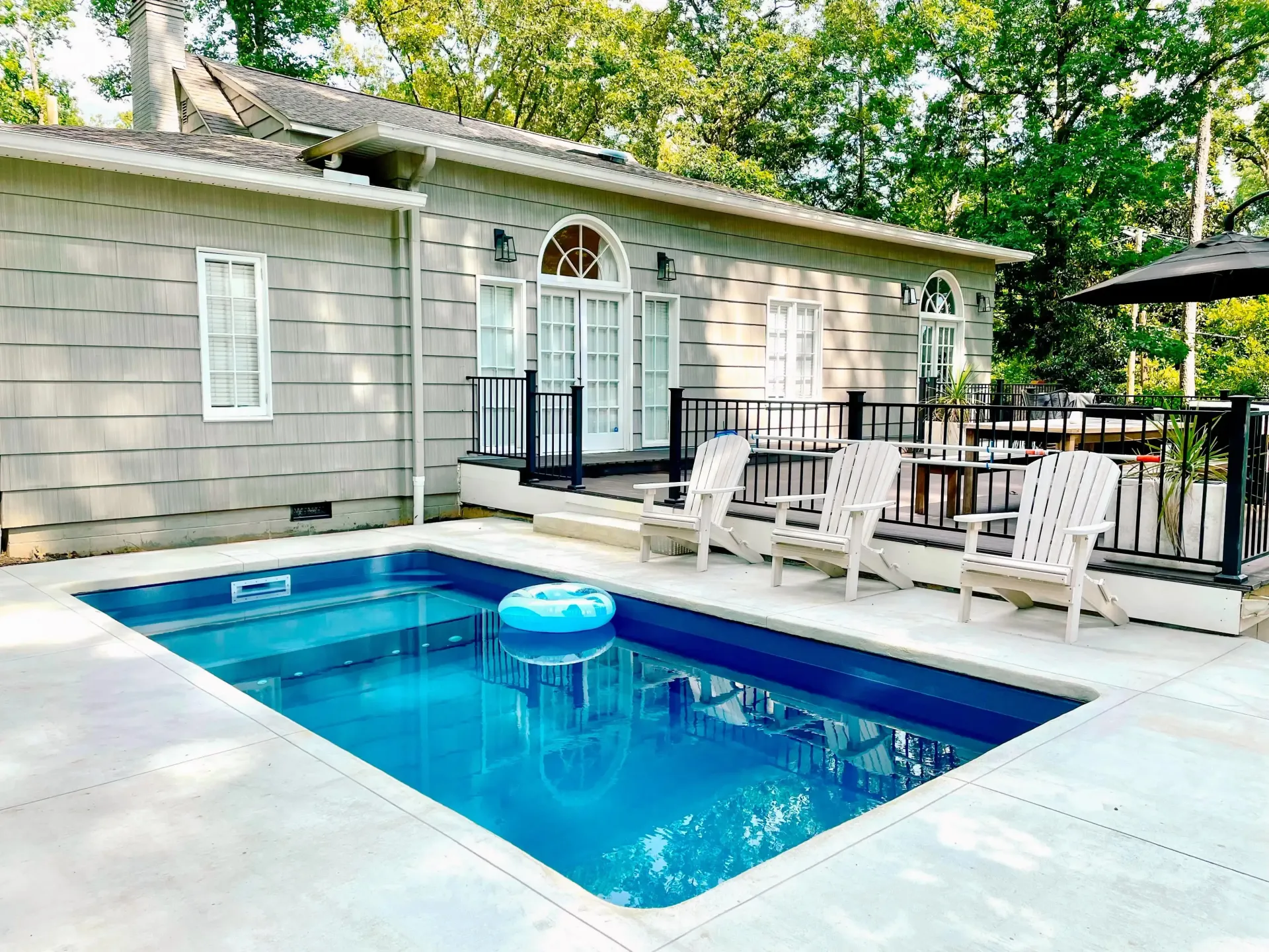 There is a large swimming pool in the backyard of a house.