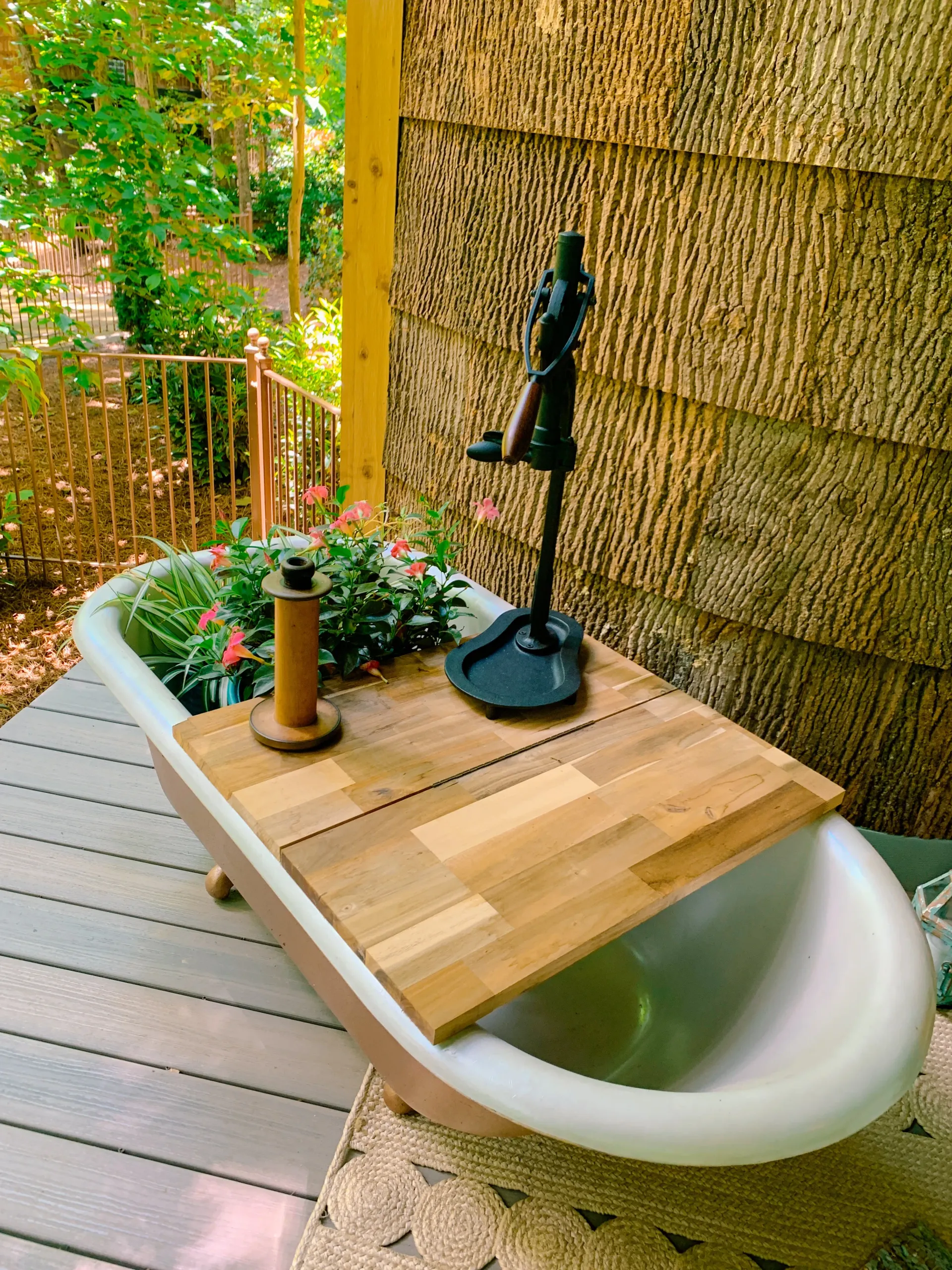 Copper clawfoot tub on porch turned into planter with vintage hand pump faucet