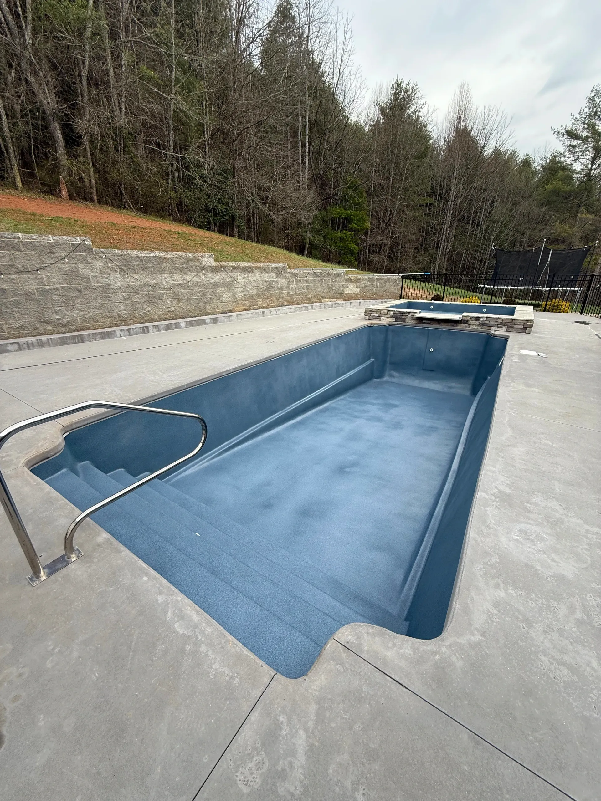 A large swimming pool is sitting on top of a concrete deck.