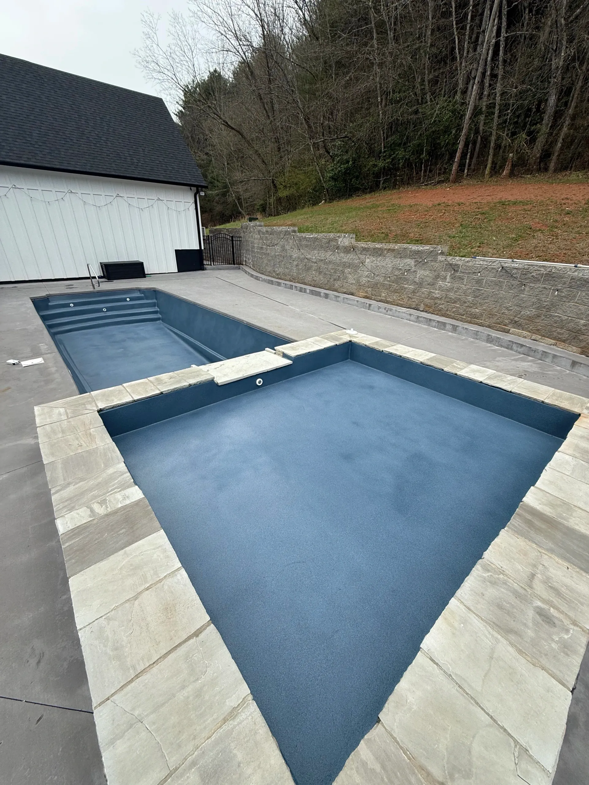 There are two swimming pools in the backyard of a house.