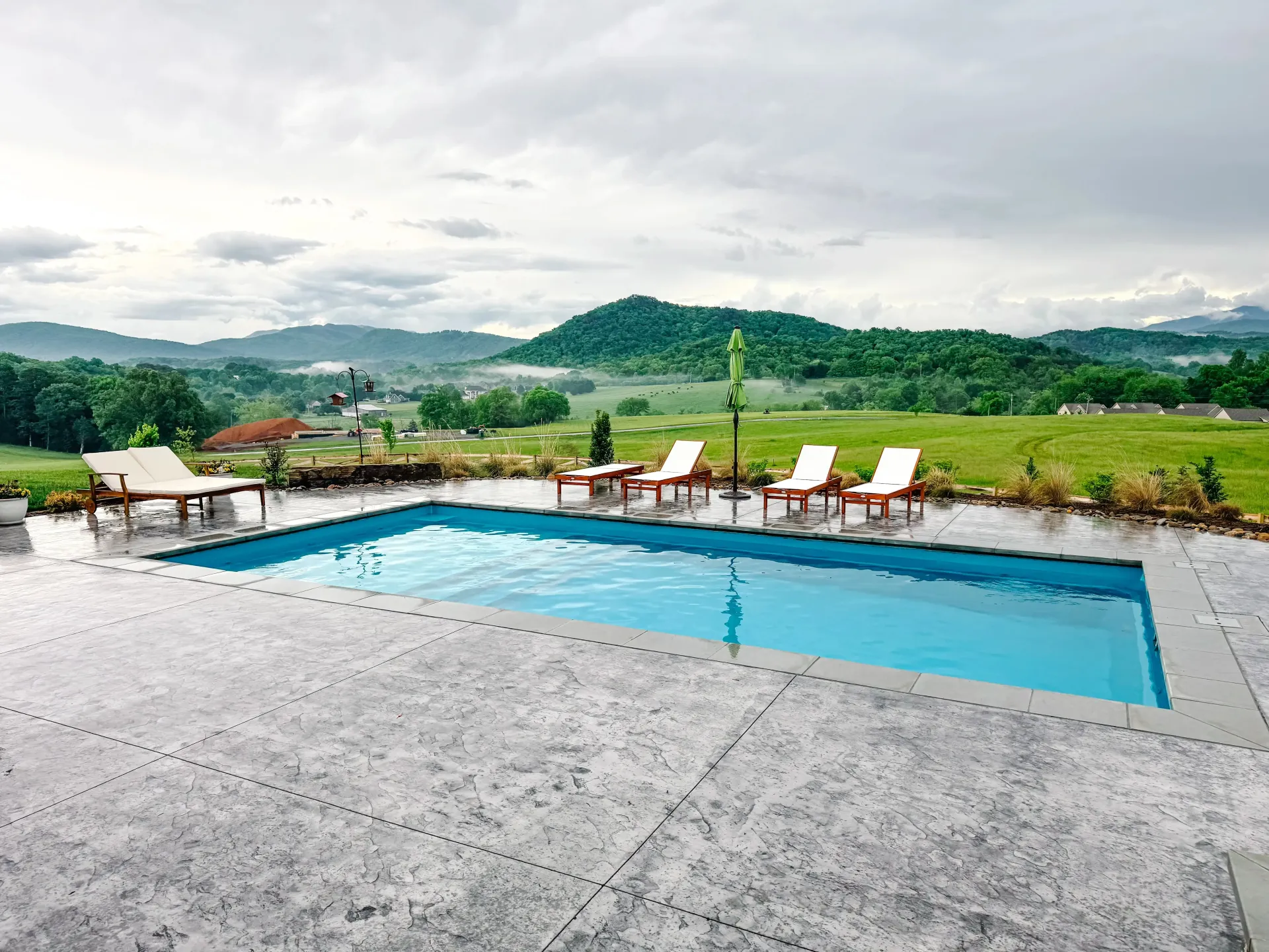 A swimming pool with chairs and umbrellas around it