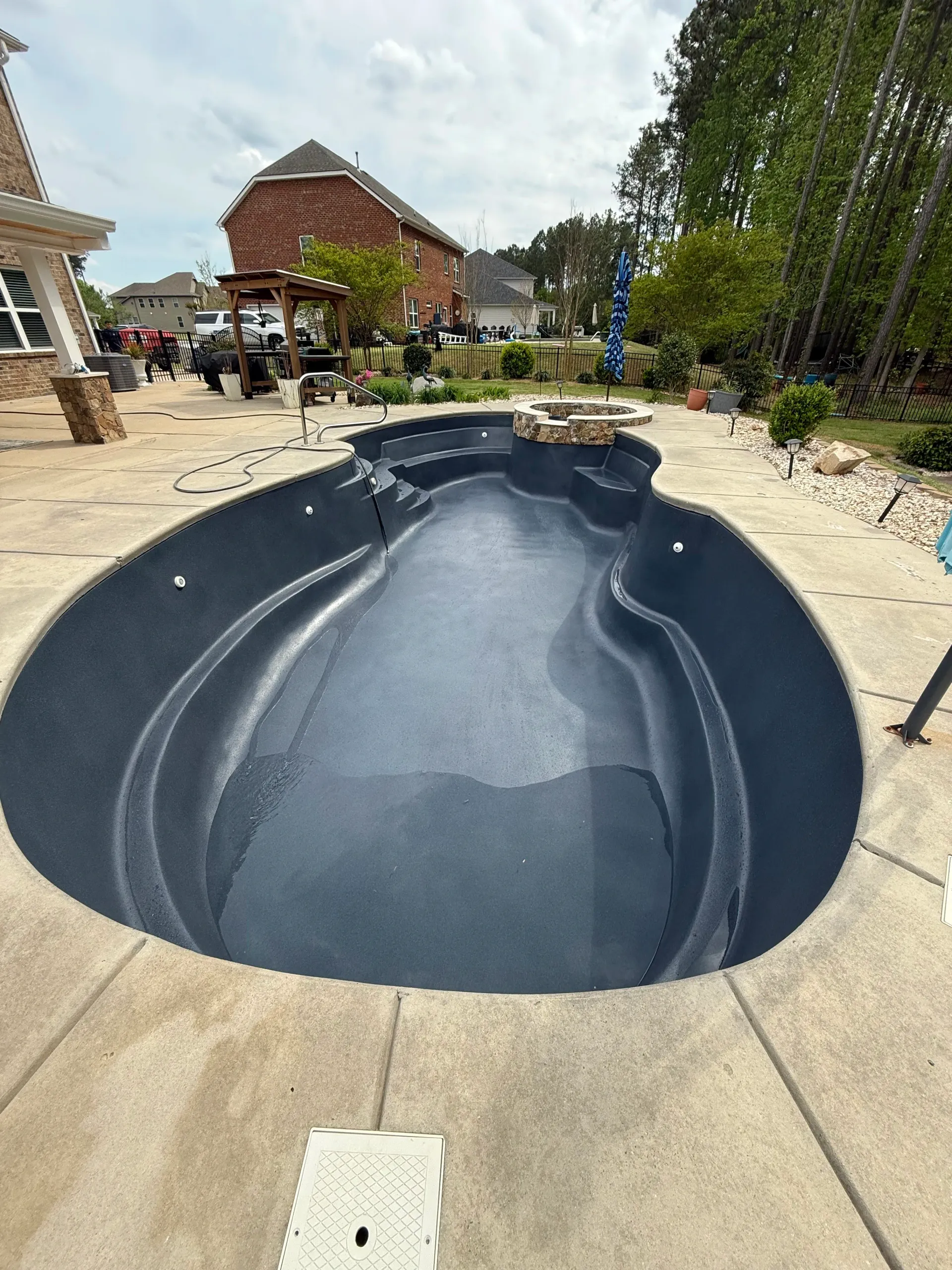 A large swimming pool is sitting on top of a concrete patio next to a house.