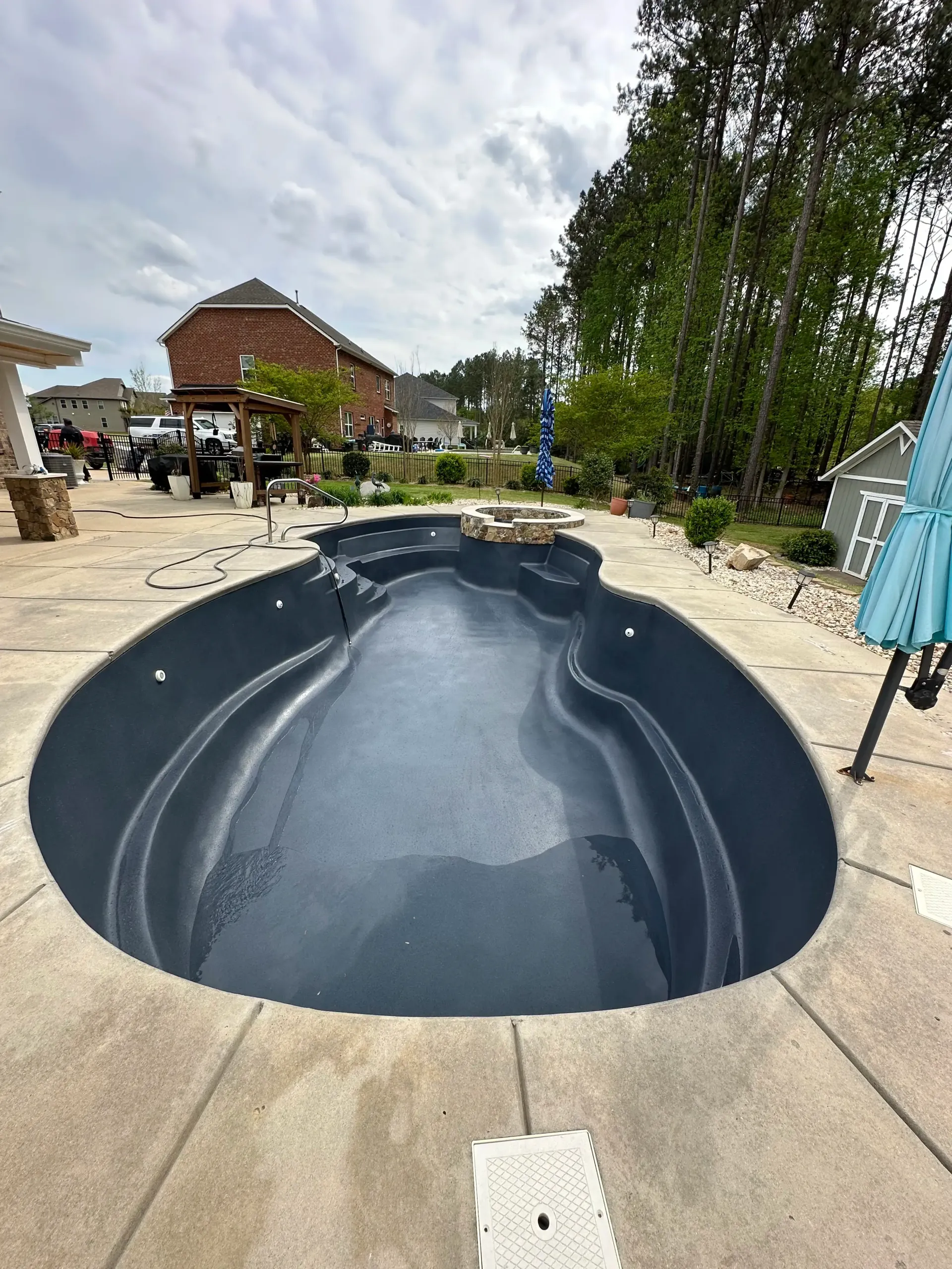 A large swimming pool is sitting on top of a concrete patio next to a house.