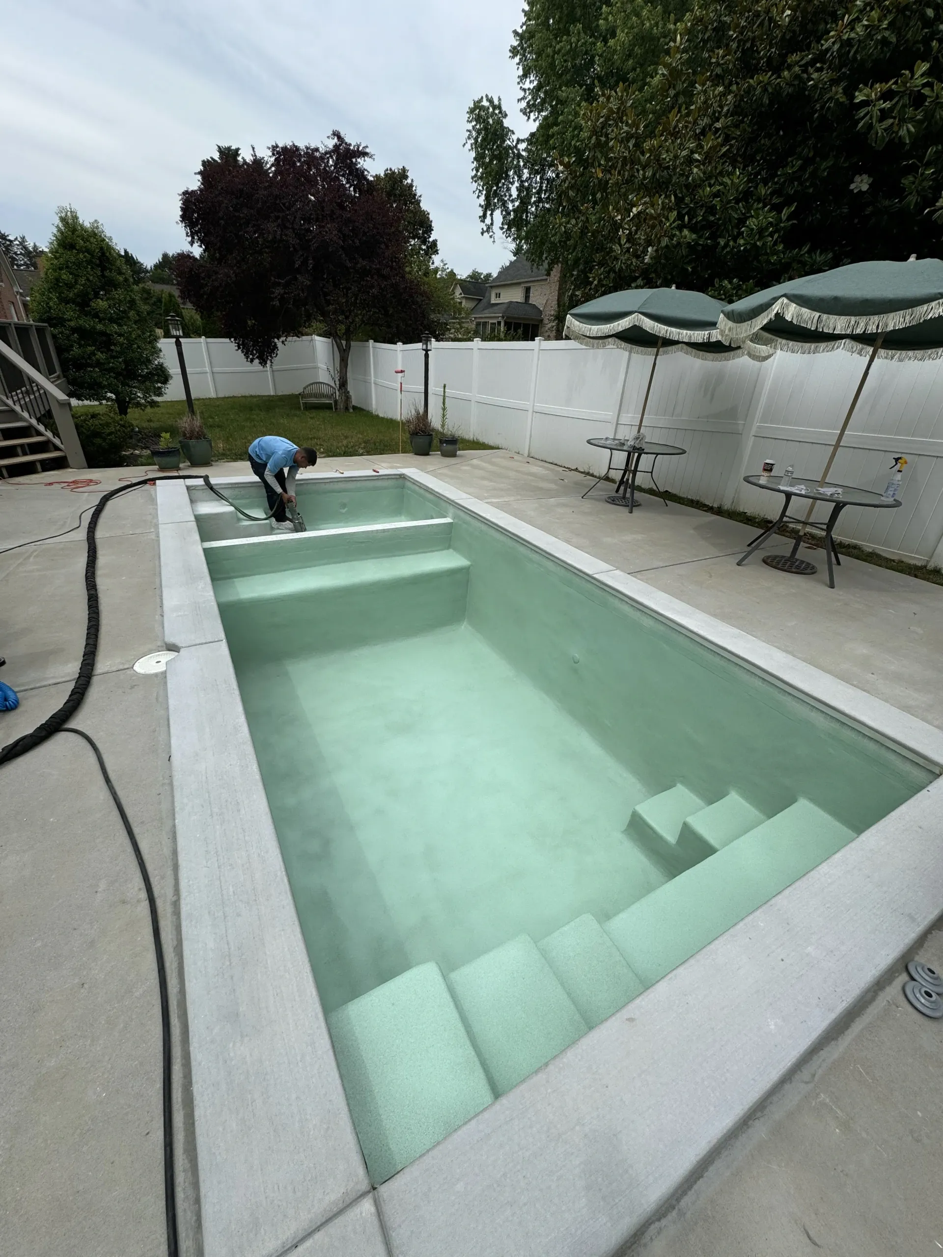 A man is working on a swimming pool in a backyard.