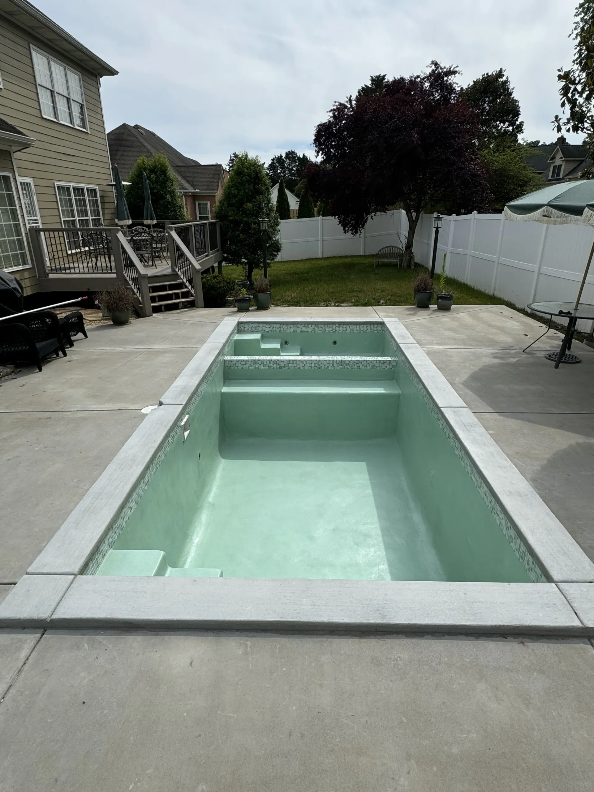 A large swimming pool is in the backyard of a house.