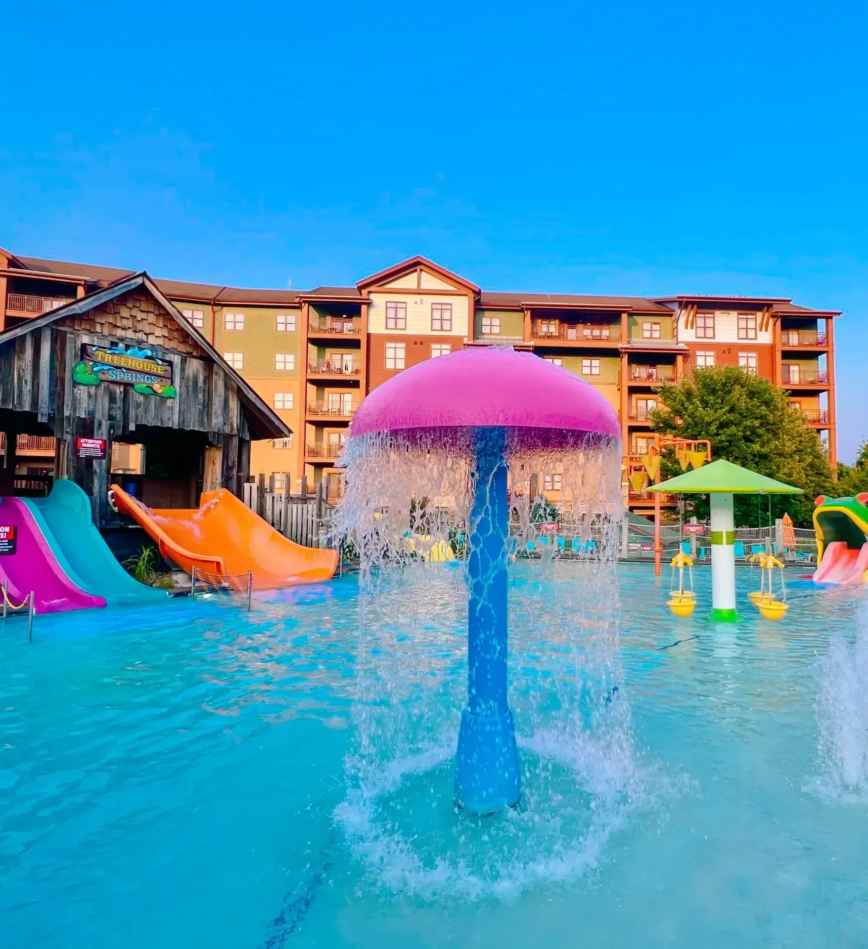 A water park with a pink umbrella in the middle of the pool.